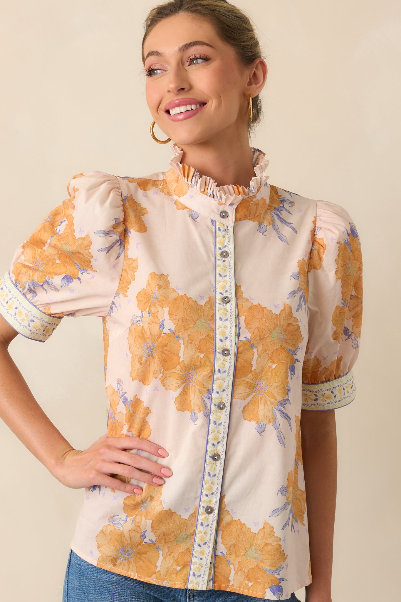 A close-up highlighting the cuffed short sleeves and contrast floral trim detail on the honey yellow floral top.