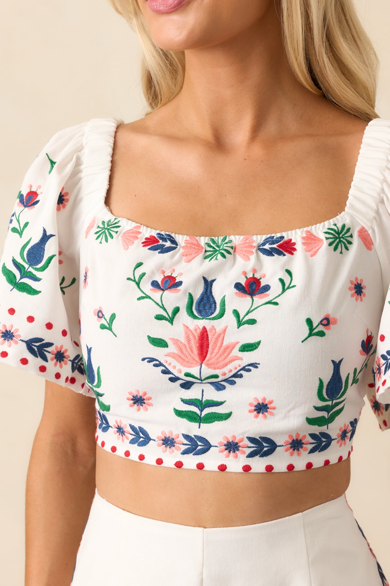 Close-up shot of the ivory top’s floral embroidery showcasing the stitching and fabric texture.