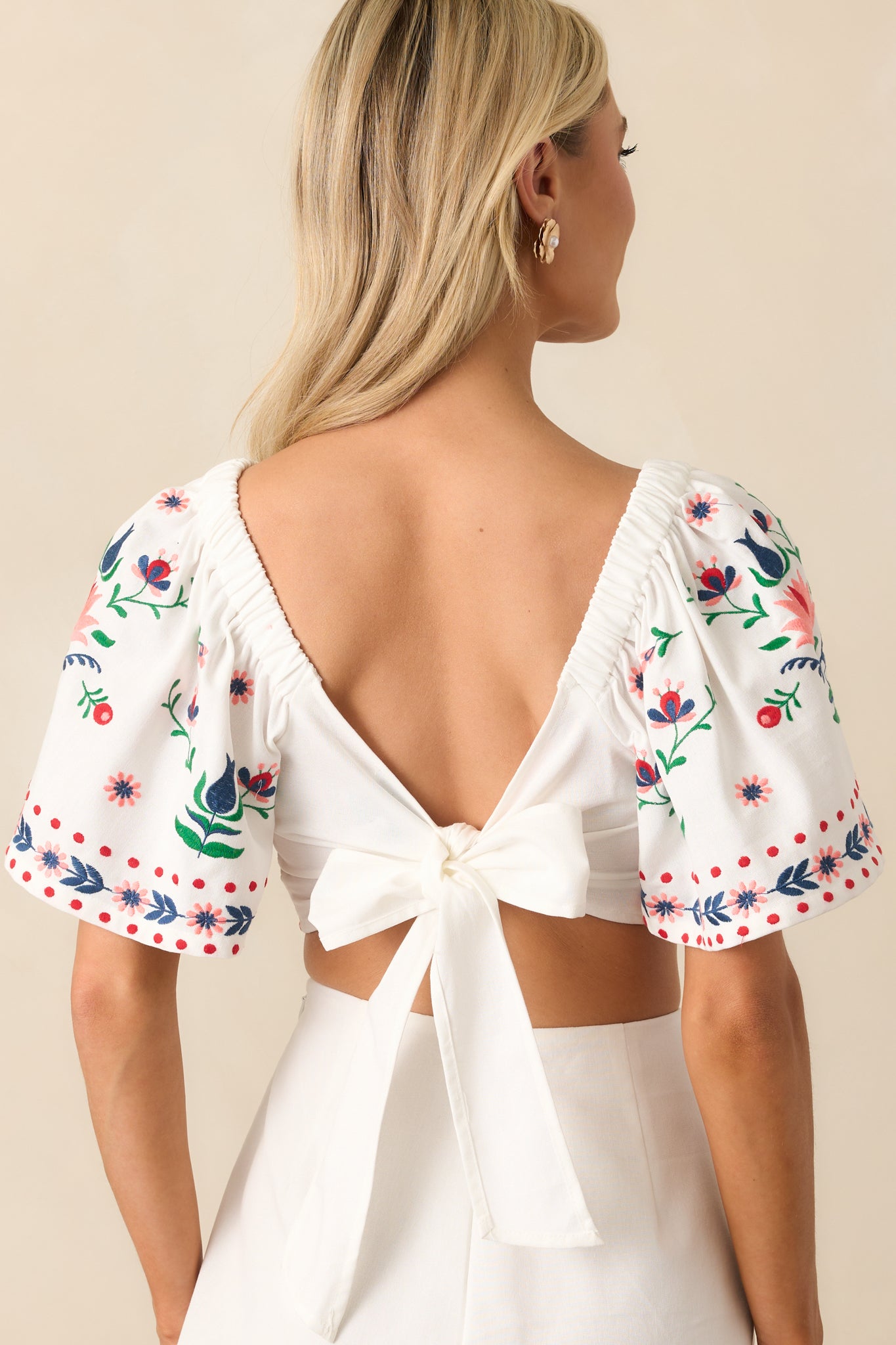 Rear view of the ivory top, featuring the open back design with self-tie detail and butterfly sleeves.