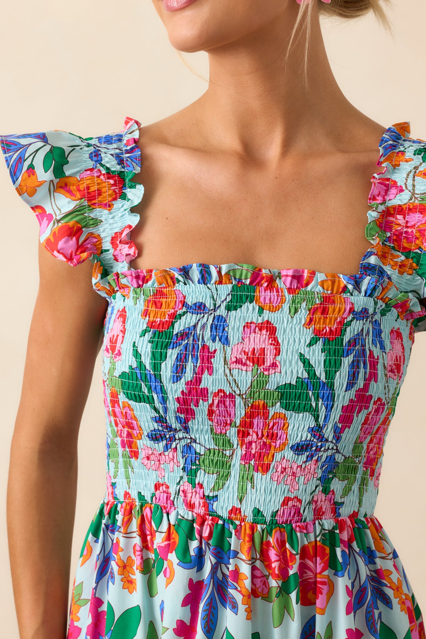 Close-up of the dress fabric showing the smocked bodice, fine ruffle trim, and soft cotton texture.