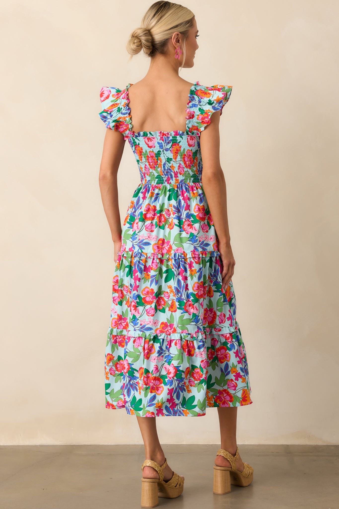 A view from behind of the light blue dress revealing the continuation of the smocked bodice and flutter sleeves.