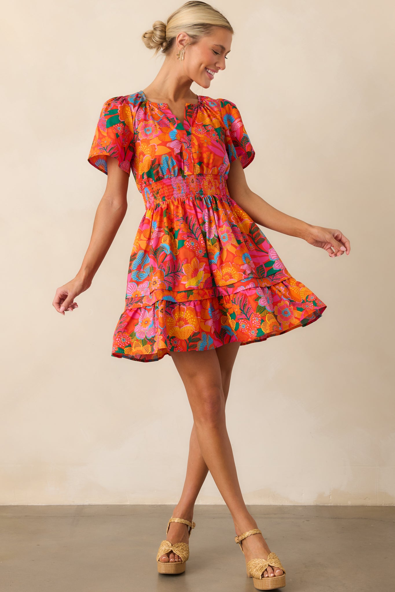 Full-length front view of the orange mini dress featuring a vibrant multicolor floral print and butterfly short sleeves.