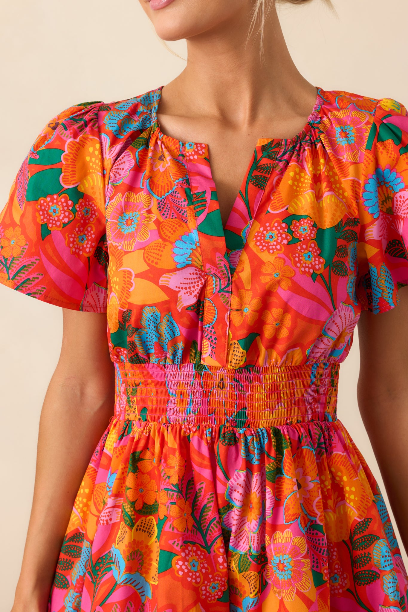 Close-up of the floral print and pin tuck detailing, showcasing the texture and vibrancy of the orange mini dress.
