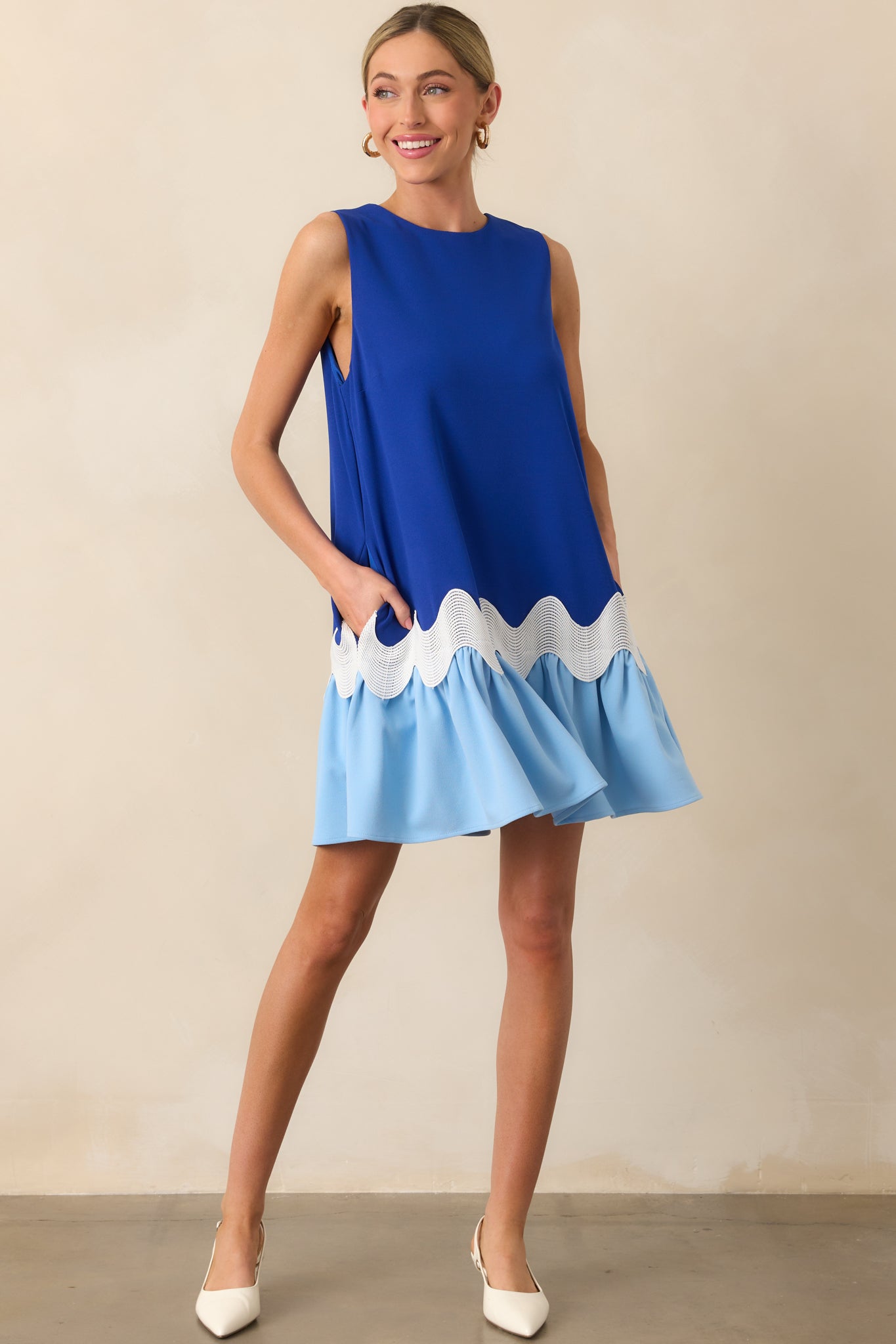 Front view of a blue mini dress featuring white ric rac trim below the waist and a lighter blue panel at the hem, showing the full silhouette.