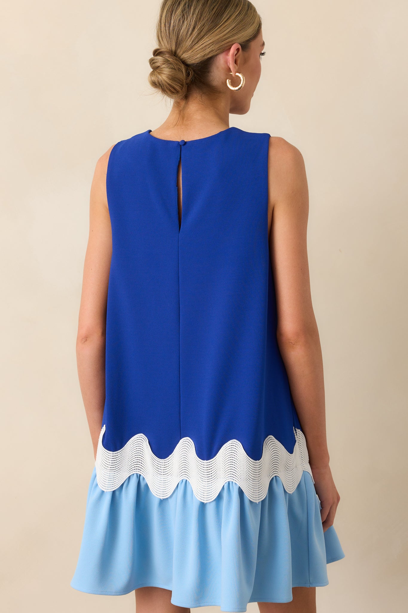 A view from behind showing the keyhole back closure of the blue dress and the color contrast between bodice and skirt.
