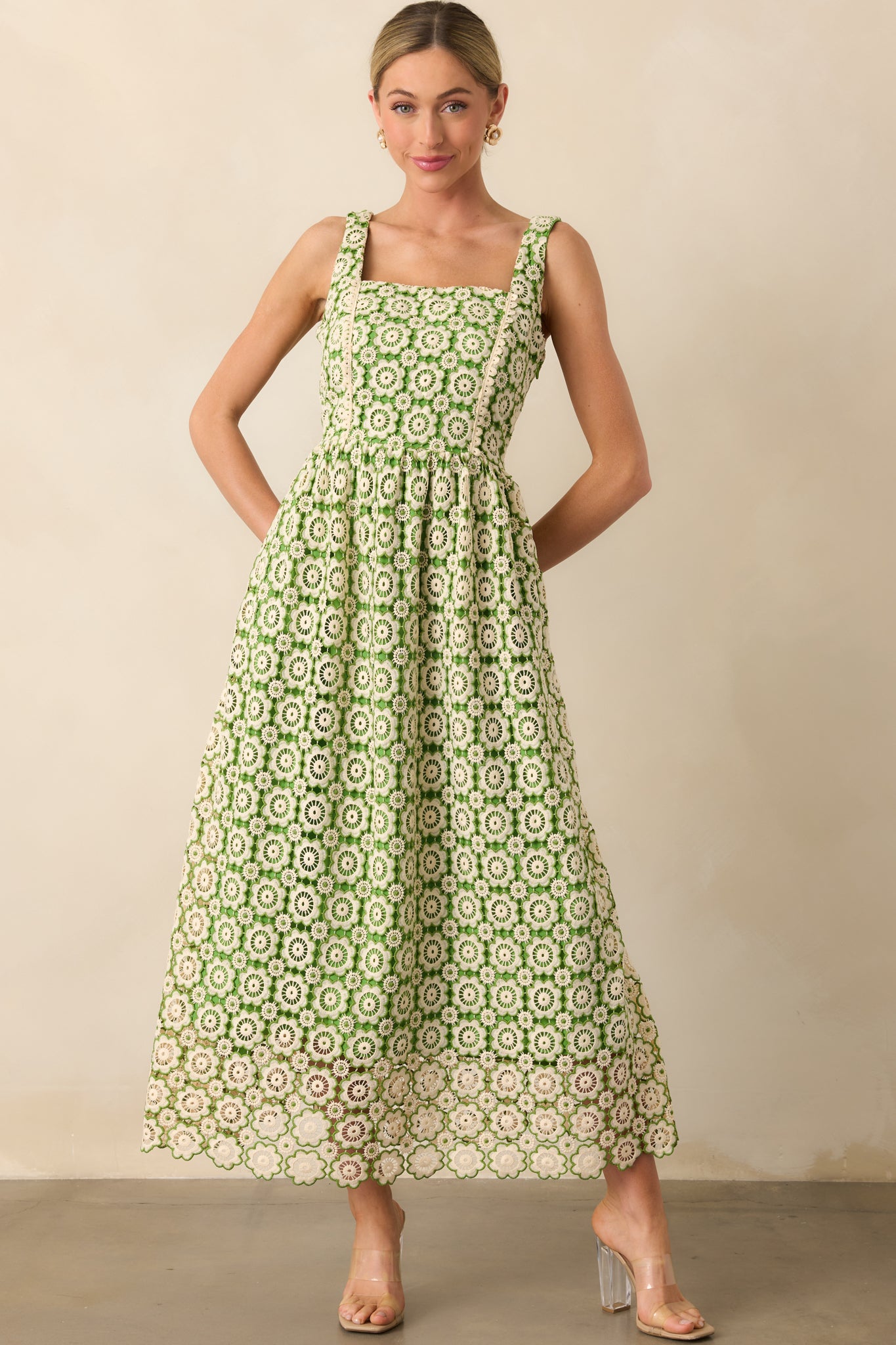 Green dress showcasing the textured floral embroidery on the fabric, with scalloped beige trim and side pockets for detail.