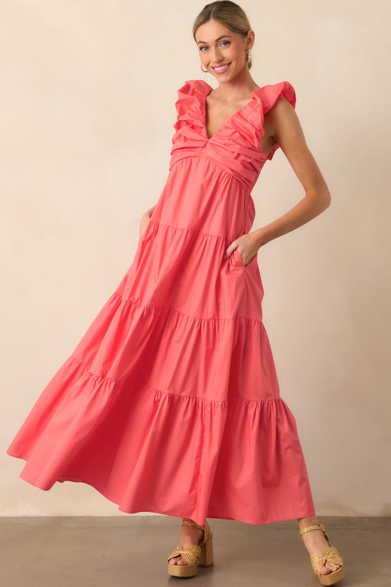 Front view of the pink coral dress featuring a deep v-neckline and tiered skirt in full length.