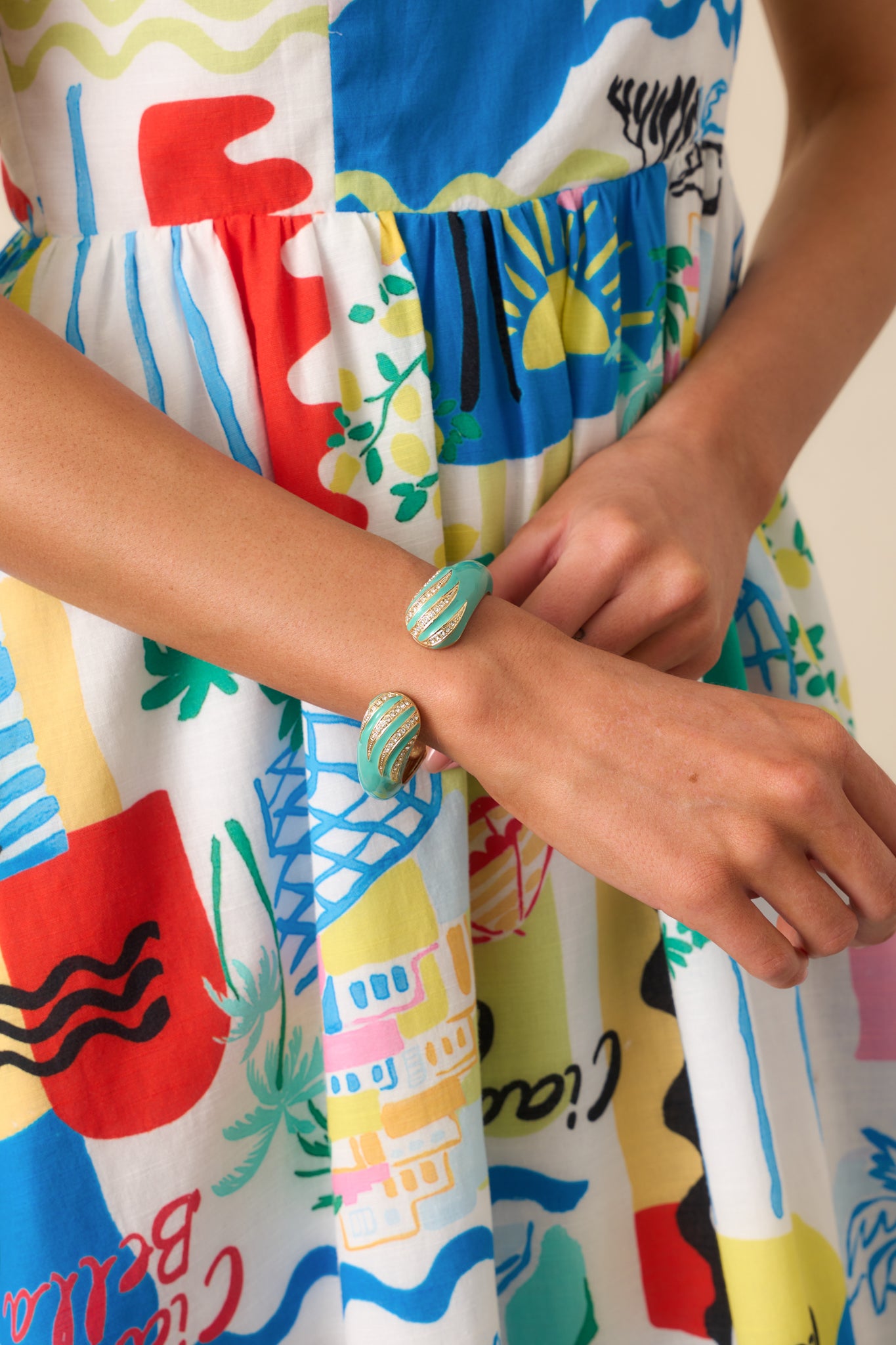 Close-up of a turquoise cuff bracelet showing one end with rhinestone detailing and glossy finish, highlighting the curved open design.