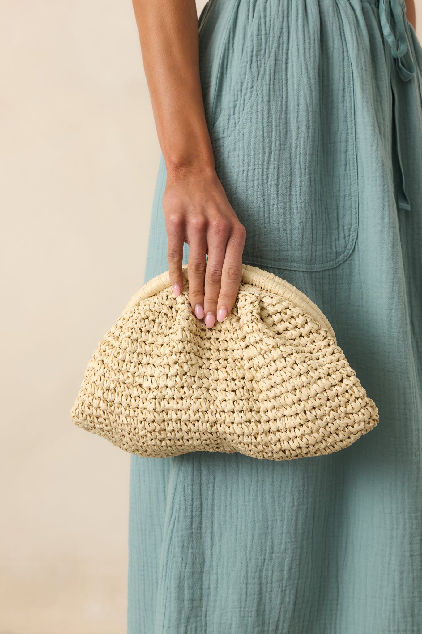 Full view of the ivory raffia slouch bag styled with its ruched shape and optional gold crossbody strap visible.