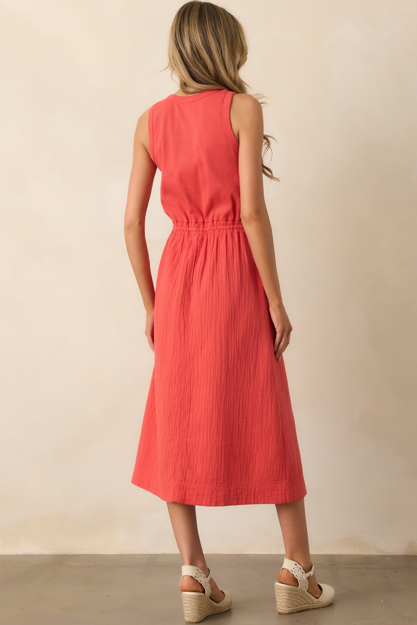 Rear view of the red midi dress showing the sleeveless cut, ribbed back panel, and the natural drape of the gauze skirt.
