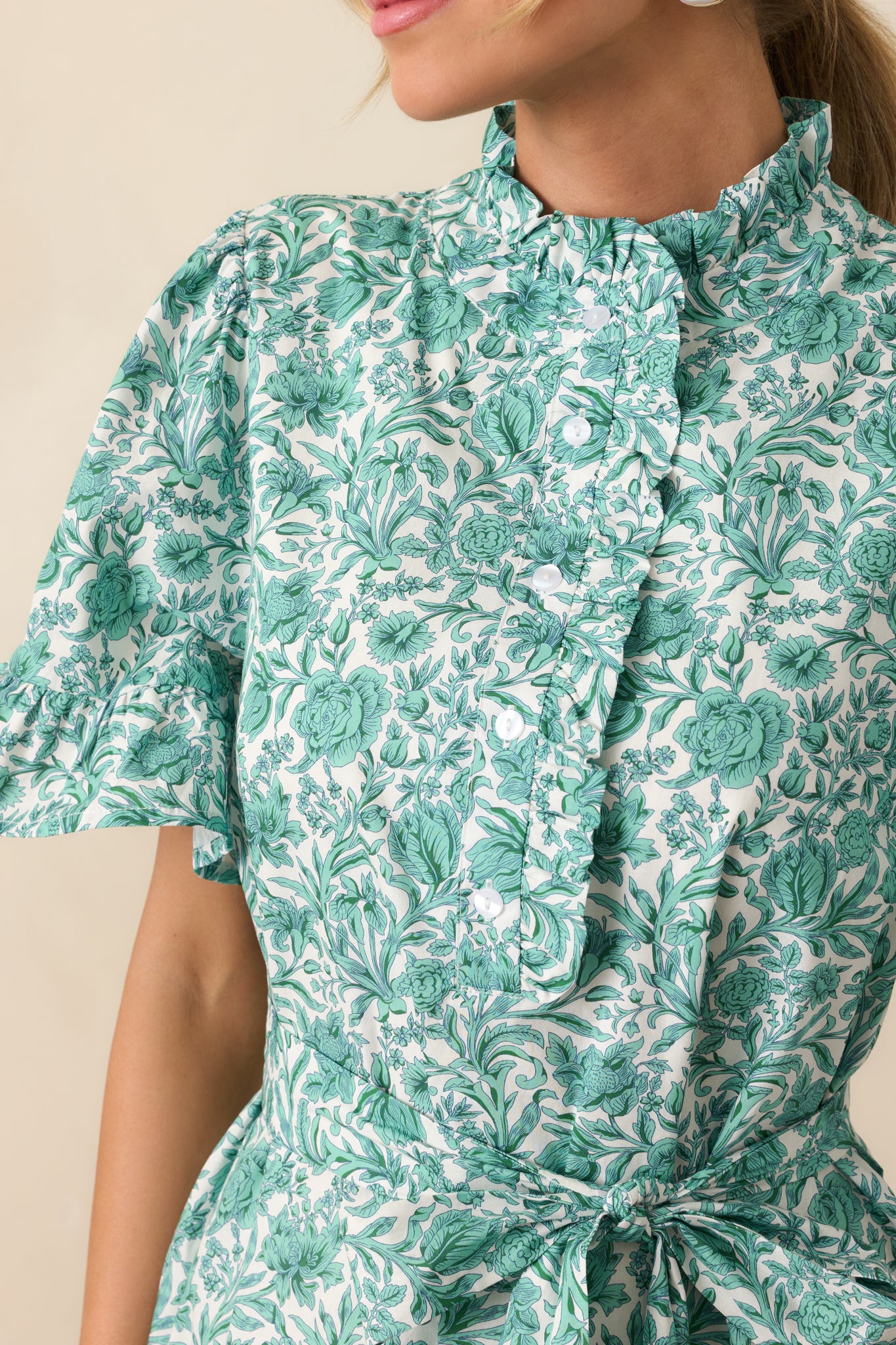 Close-up of the high ruffle neckline and functional buttons, showing texture and construction.