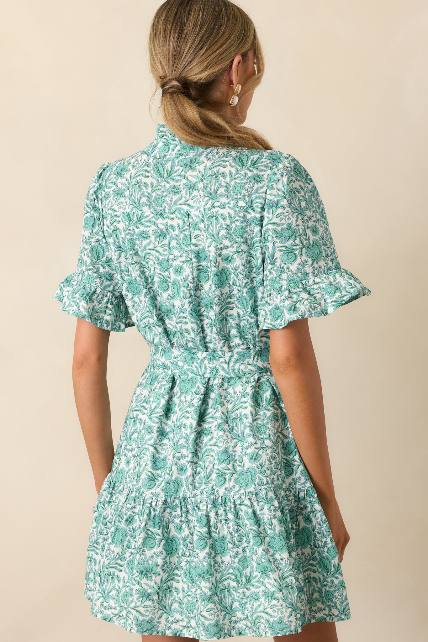 A view from behind of the mini dress, showing the gathered waistline and tiered skirt with soft ruffle hem.