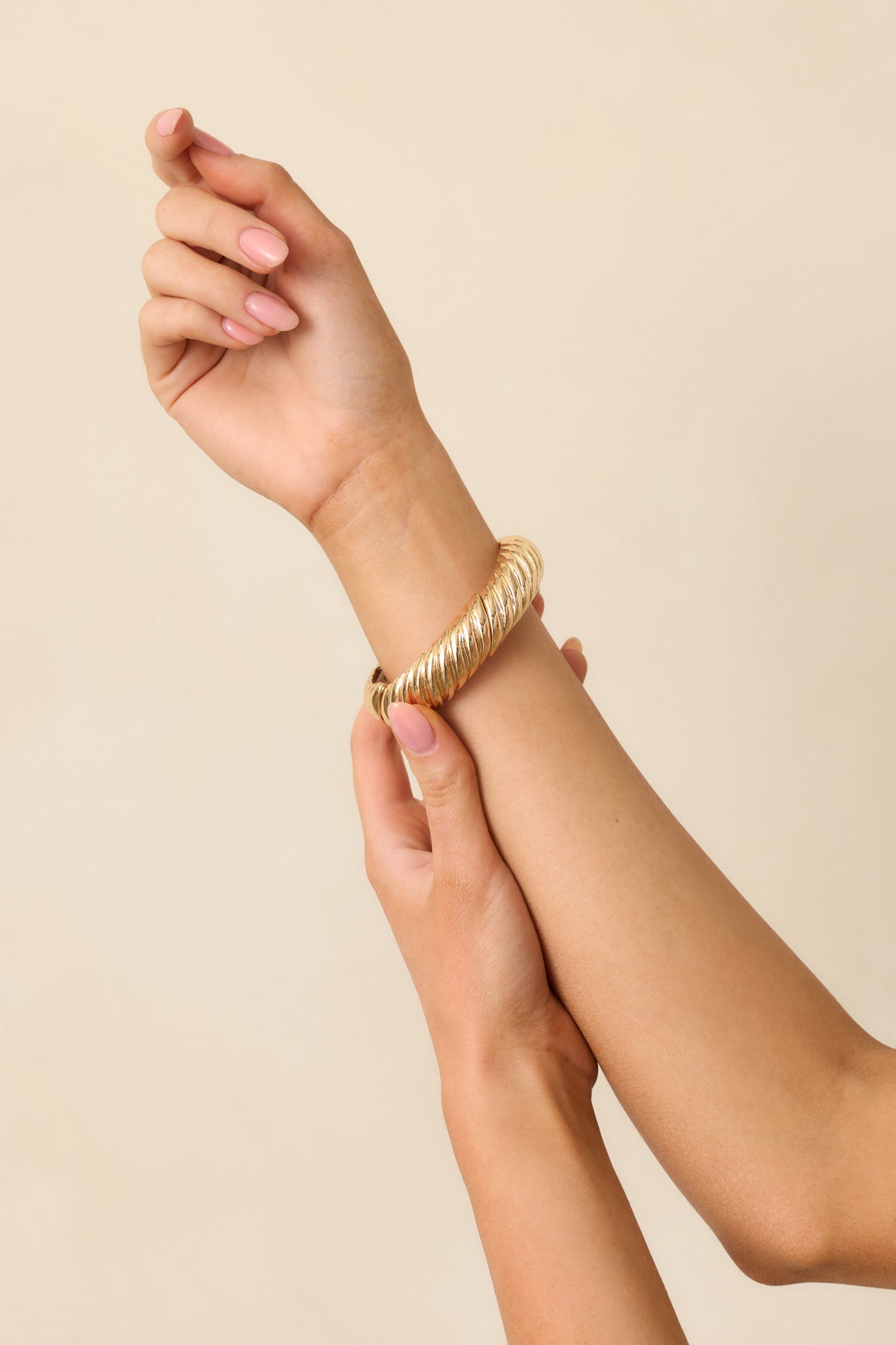 Cropped view of gold bracelet showcasing twisted hardware and split design around the wrist.