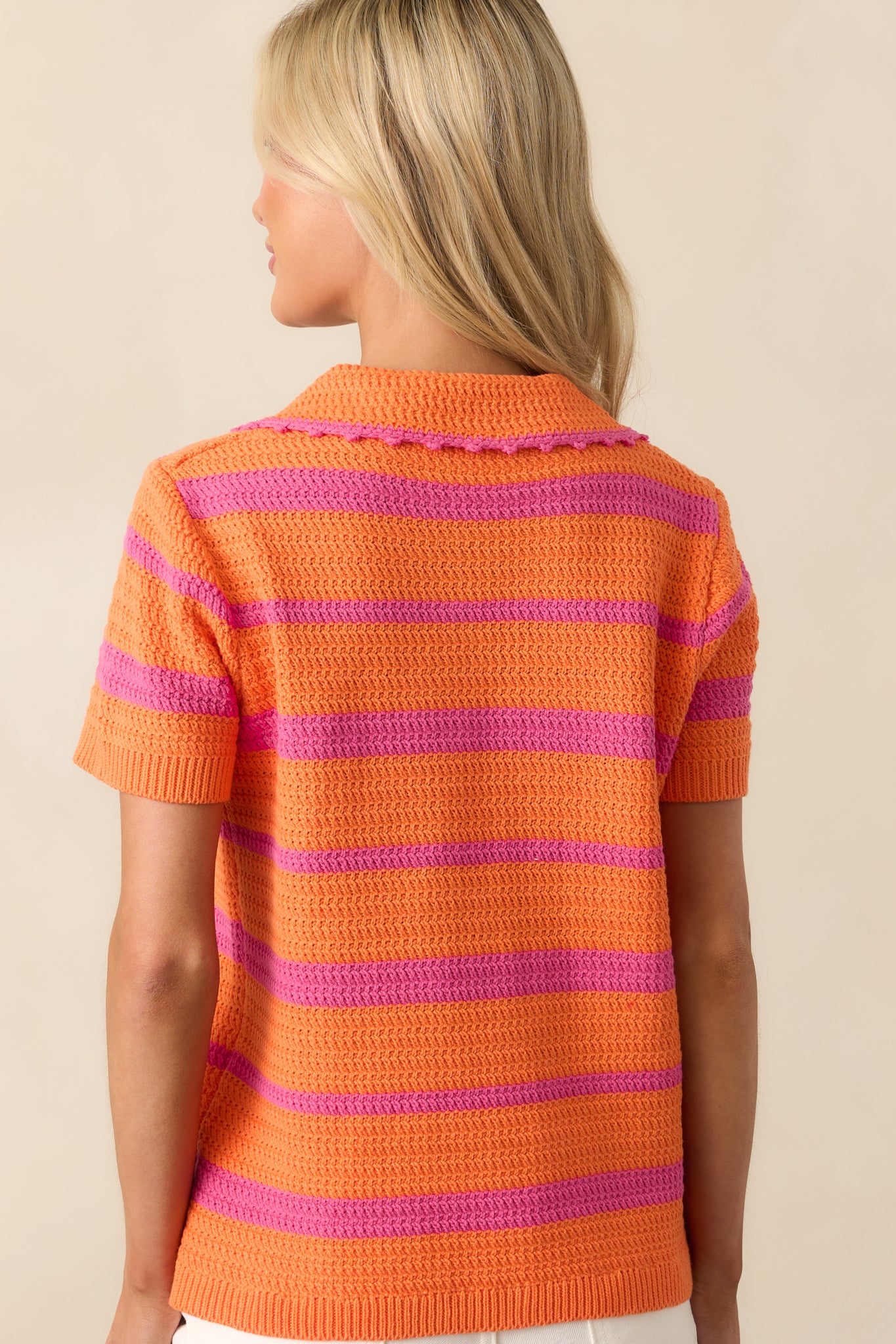 View from behind of the striped knit top, showing the continuation of the orange and pink pattern and short sleeves.