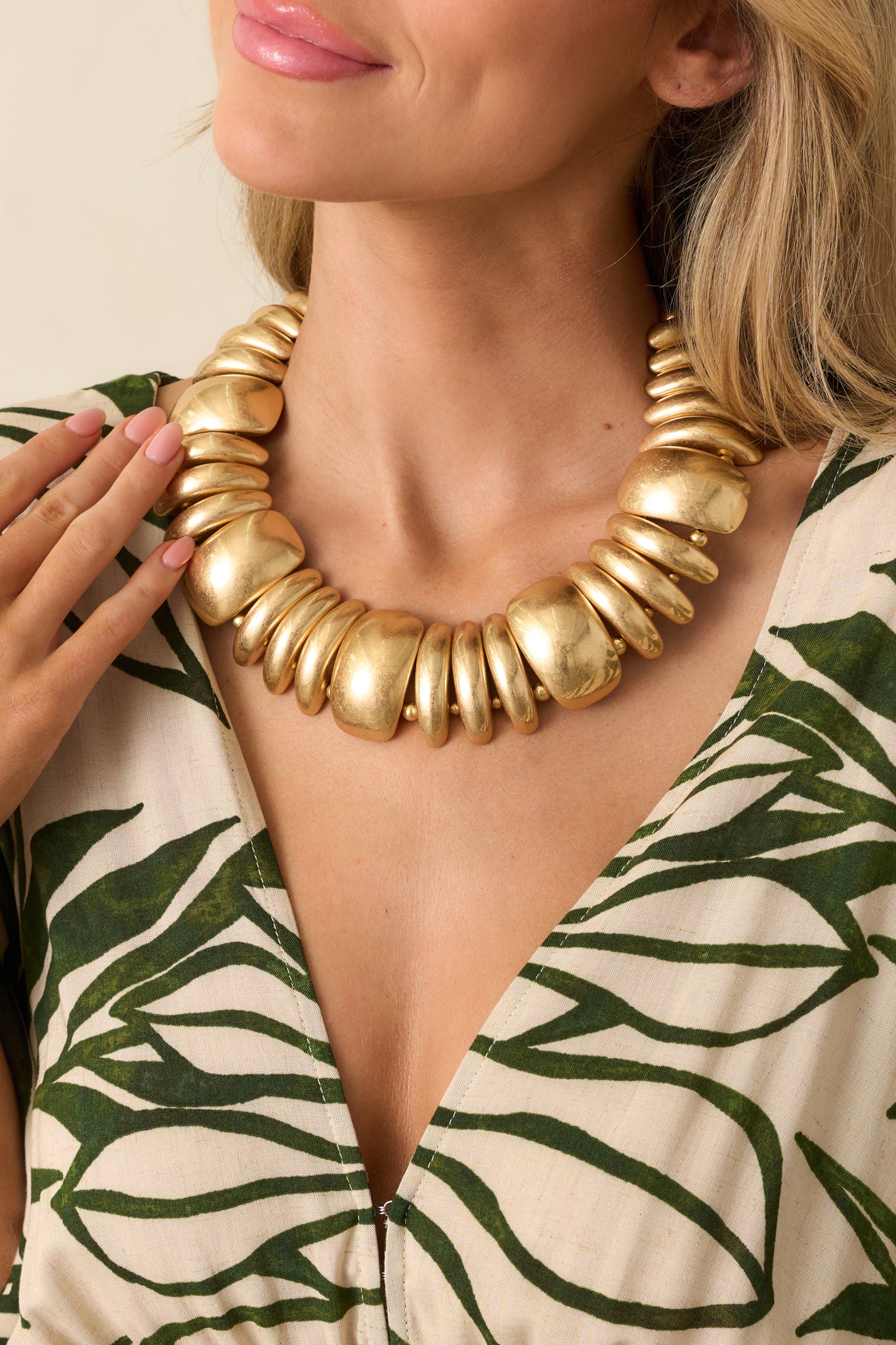 Neckline view of the gold necklace showcasing its bold, chunky collar design and graduated metallic gold beads.