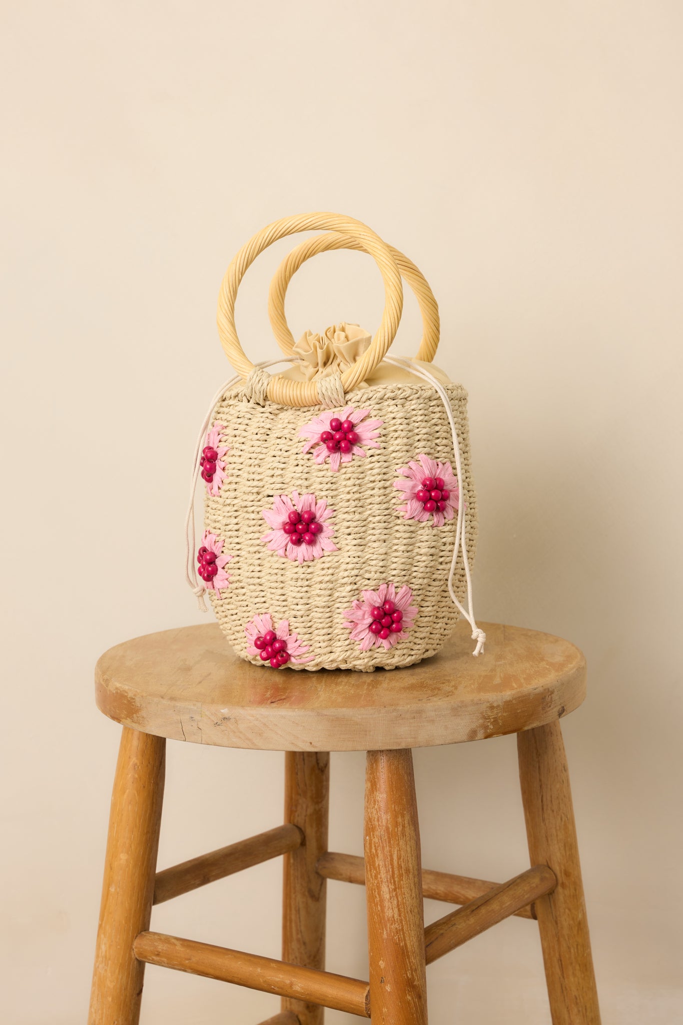 A close-up of the circular wicker handles and top portion of the bag, highlighting the craftsmanship and drawstring closure.