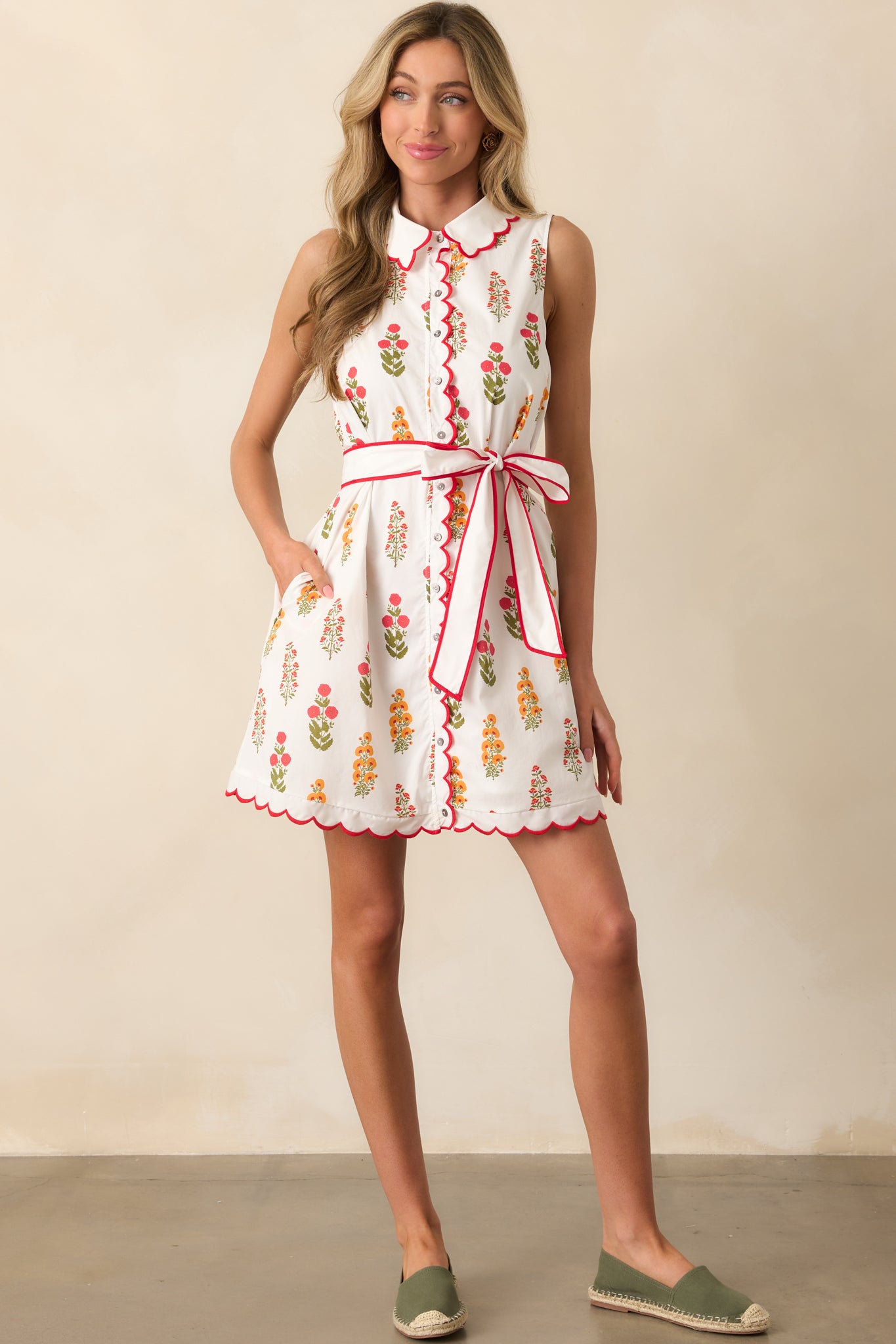 Front view of a red floral mini dress featuring a sleeveless cut and scalloped hemline