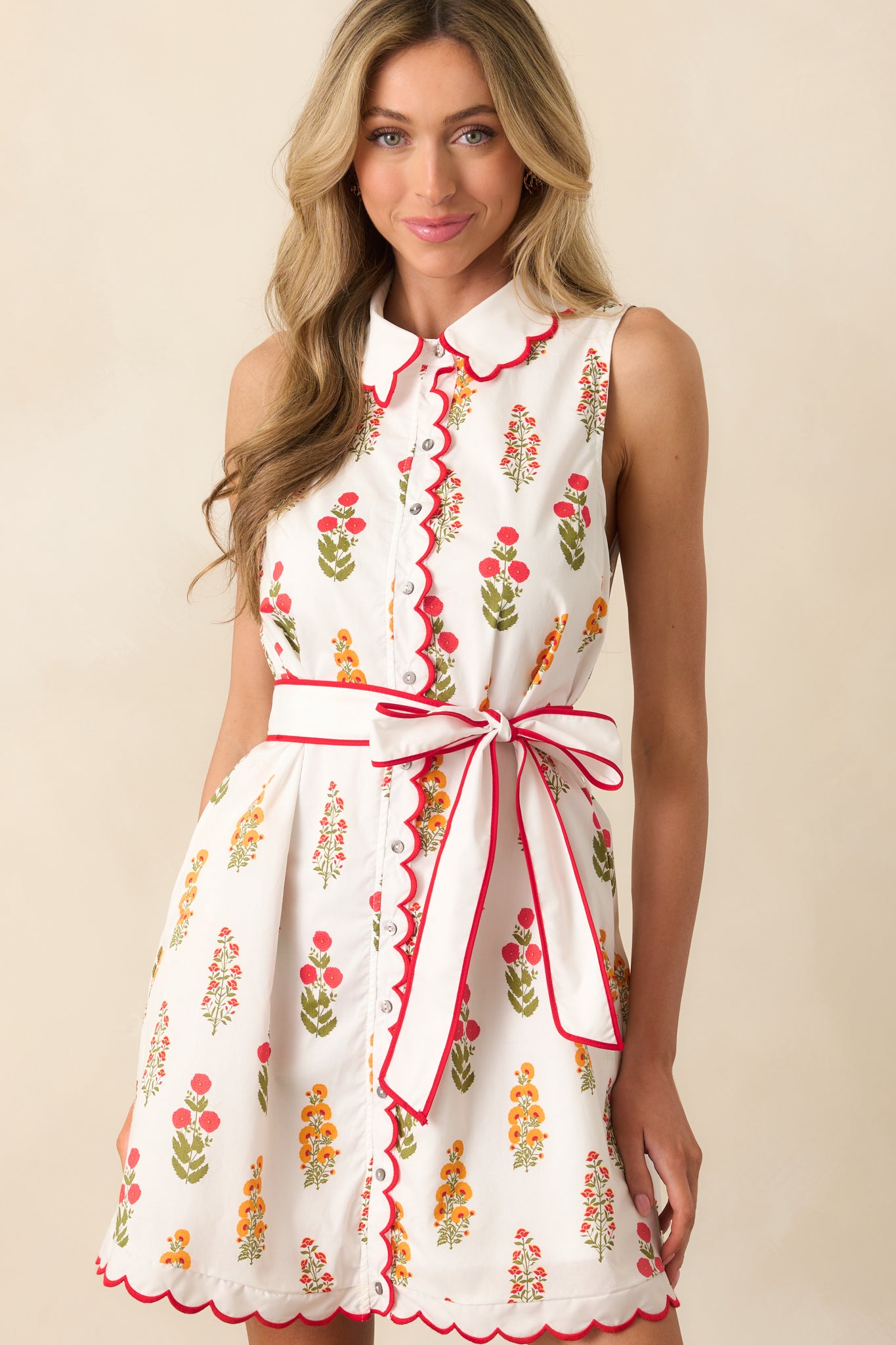 Close-up of the waist of the red floral dress showing the self-tie belt and part of the button front.