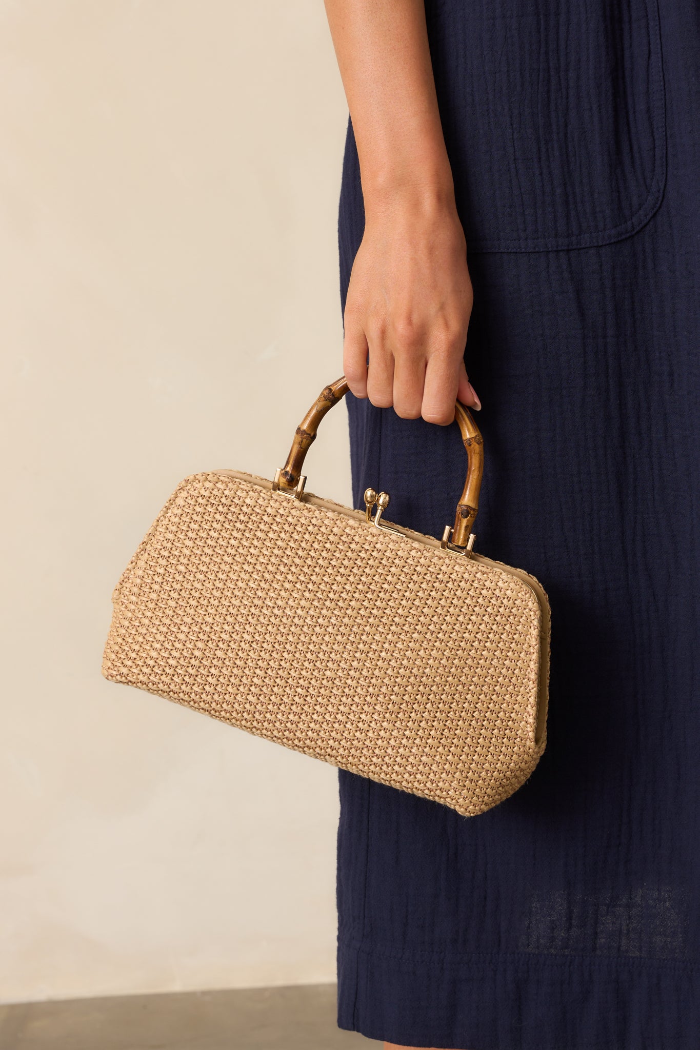 Side view crop of the handbag showing the woven exterior and hints of the gold chain crossbody strap.
