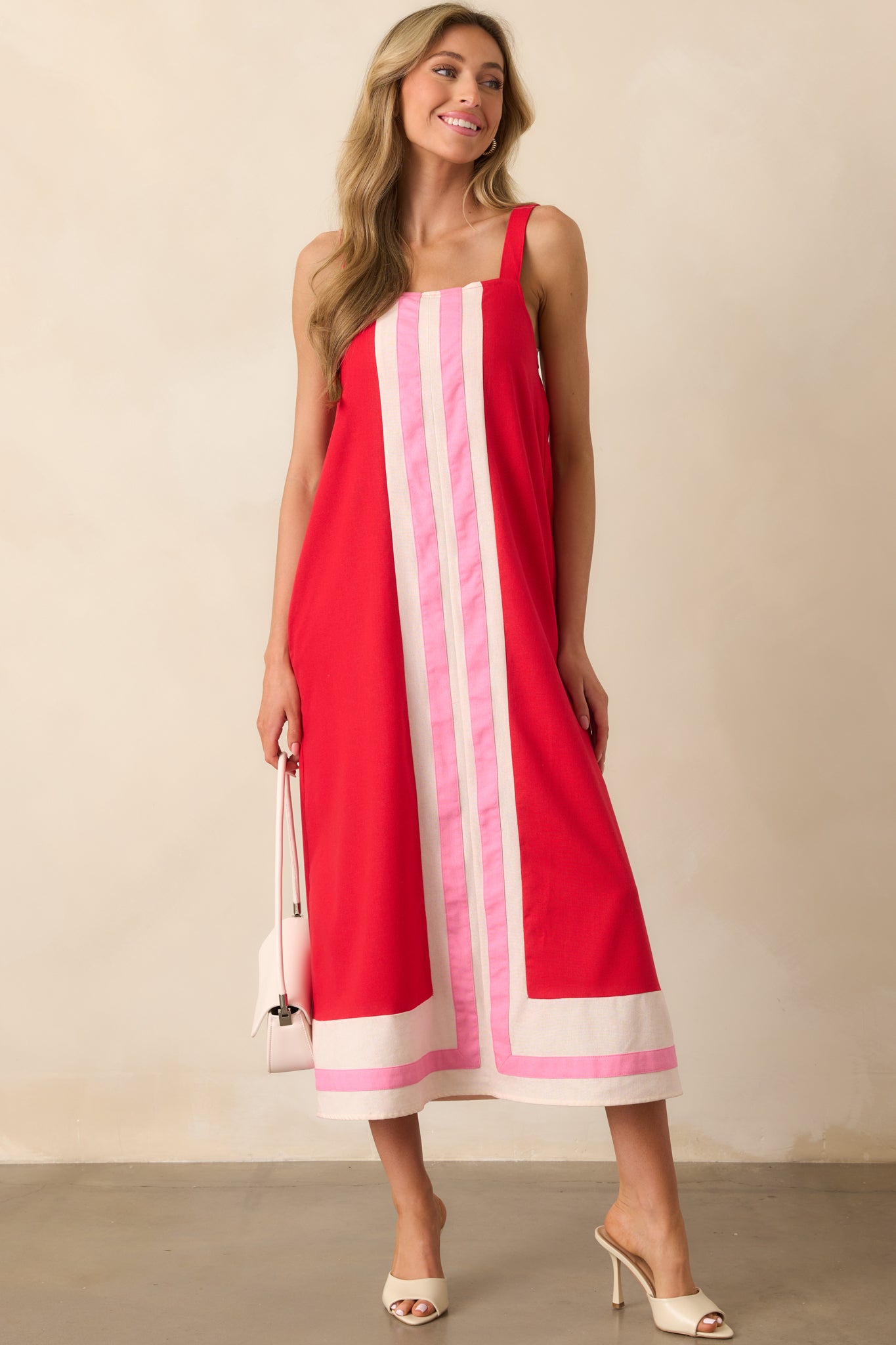 Full-length front view of the red maxi dress featuring a square neckline and color-blocked ivory and pink stripe hem.