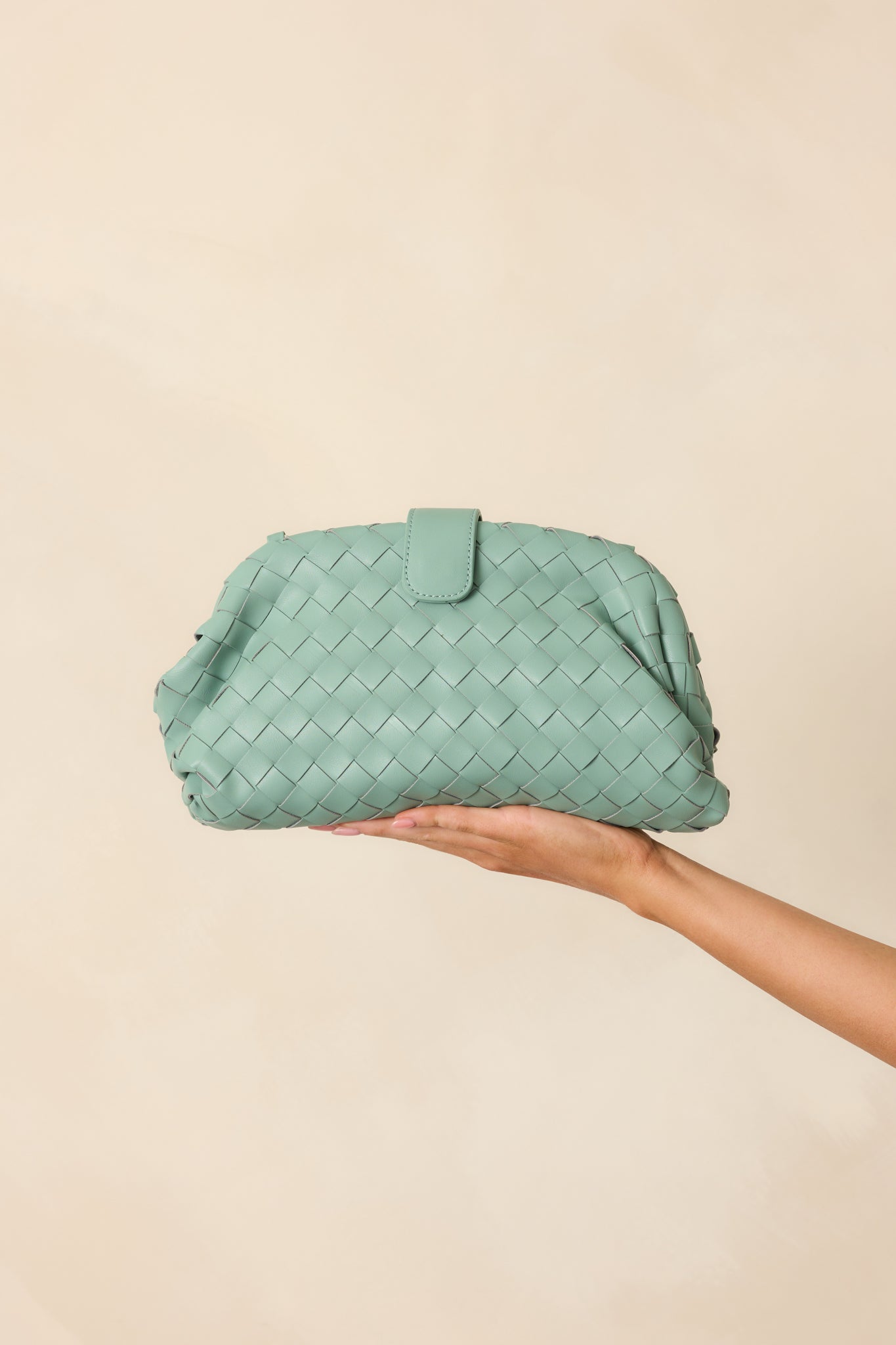 Muted mint green woven handbag with braided mint and silver shoulder strap, shown hanging at full length with flap closure visible.