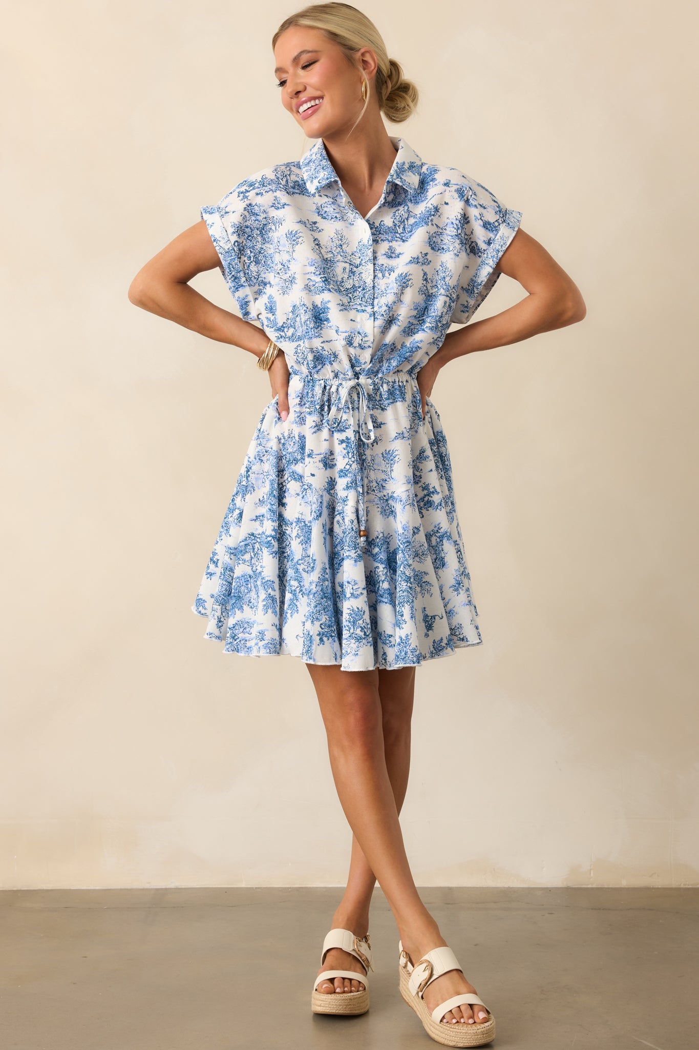 Mini dress with button-down front, tied waist, and short cuffed sleeves displayed in a full length front shot.