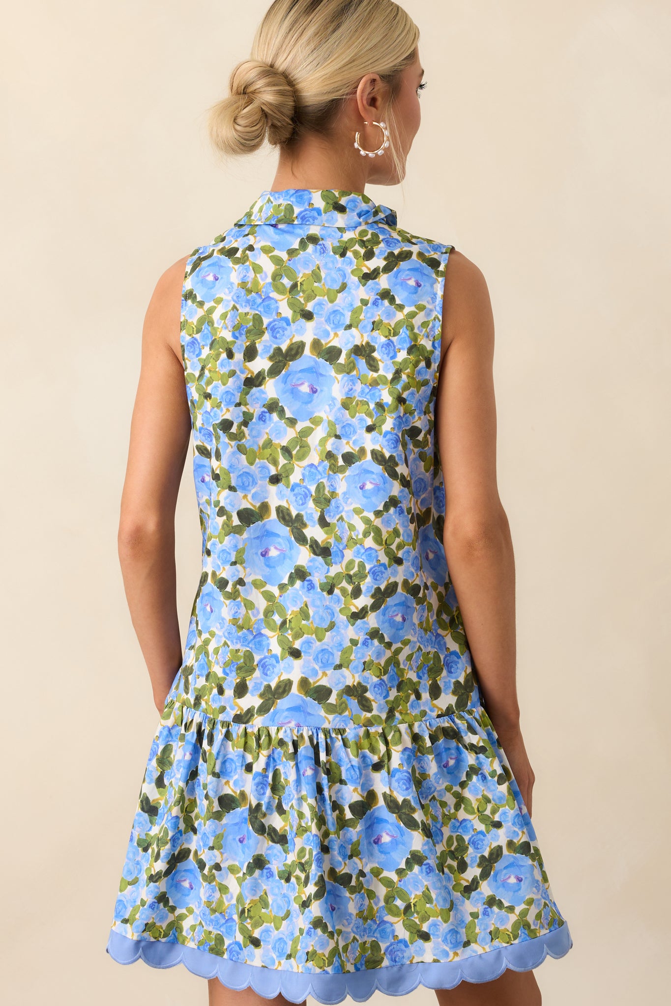 A view from behind of the mini dress, displaying continued floral print and flowy sleeveless silhouette.