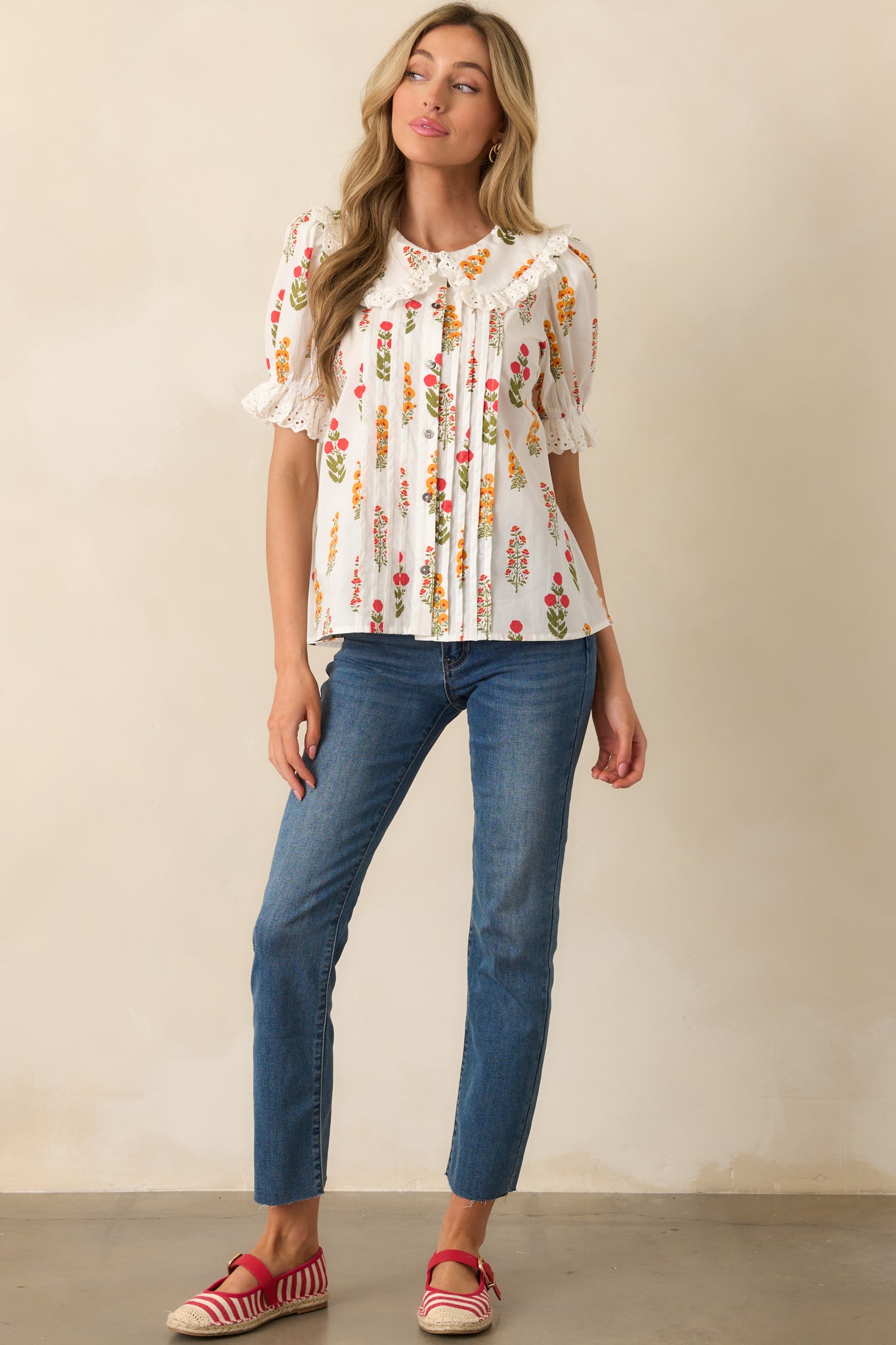 A front view of top featuring a peter pan style collared neckline, functional button front, and short puff sleeves with lace trim detailing.