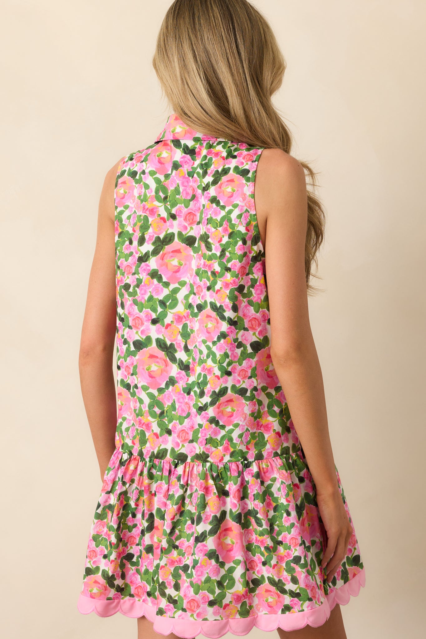 View from behind of the pink mini dress displaying the sleeveless cut, floral print, and tiered design.