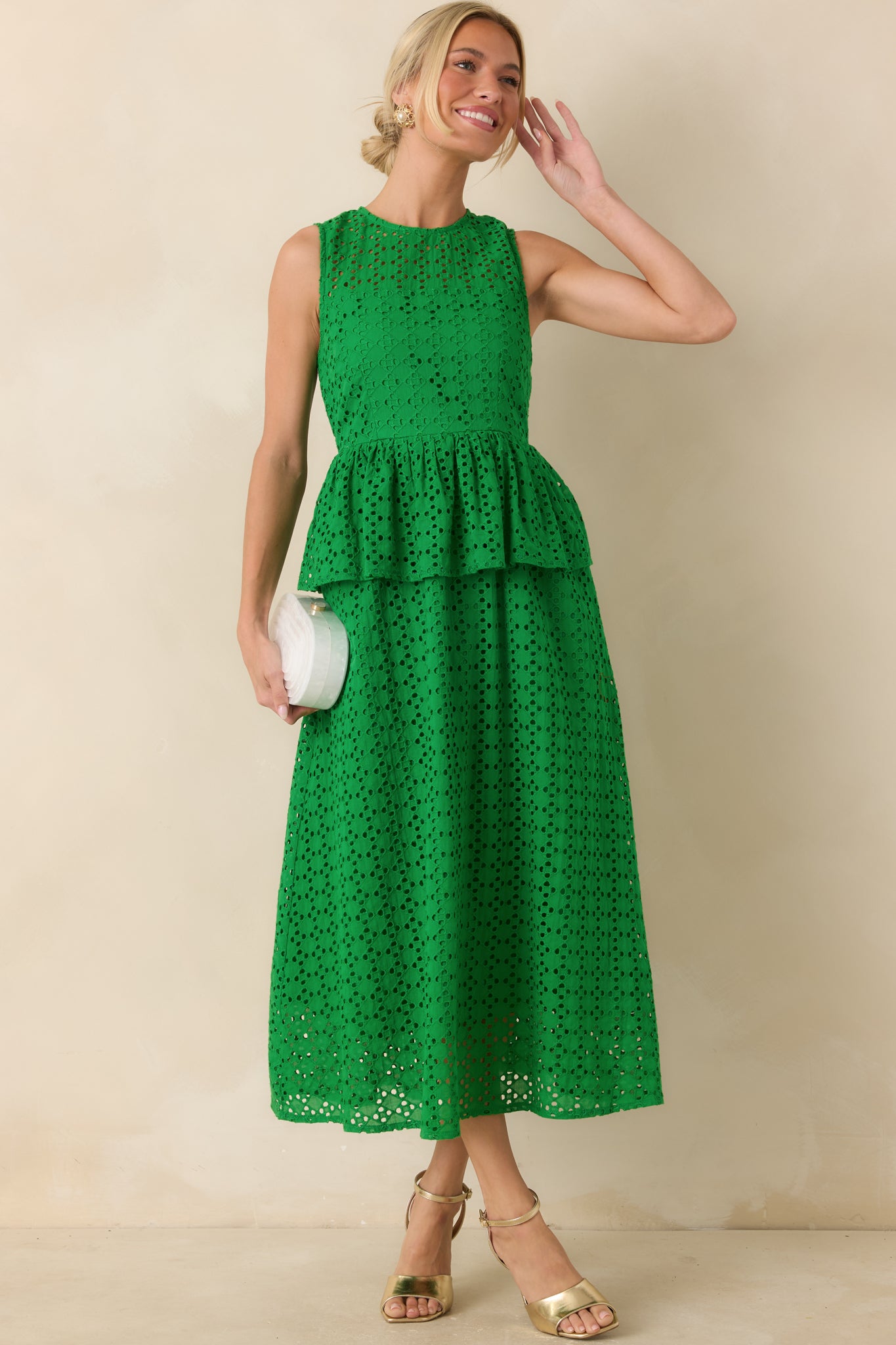 Sleeveless green eyelet dress showcasing a peplum waist detail, fully lined construction, and a flowing midi-length skirt.