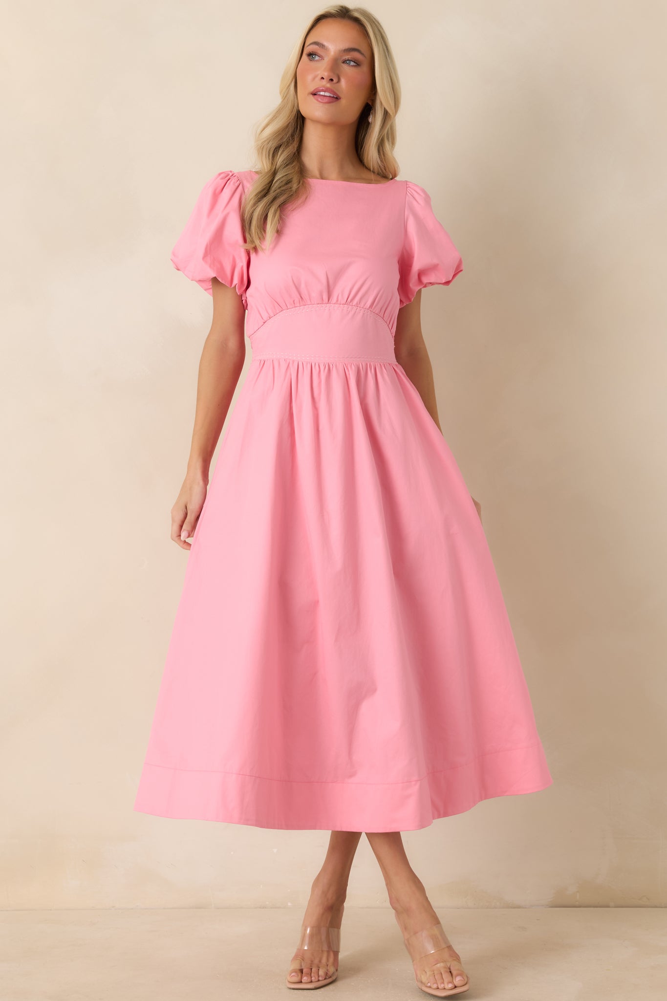 Pink cotton midi dress featuring puff sleeves with elasticized cuffs, an empire waist with contrast stitching, and a lined midi-length skirt with a soft, flowing silhouette.