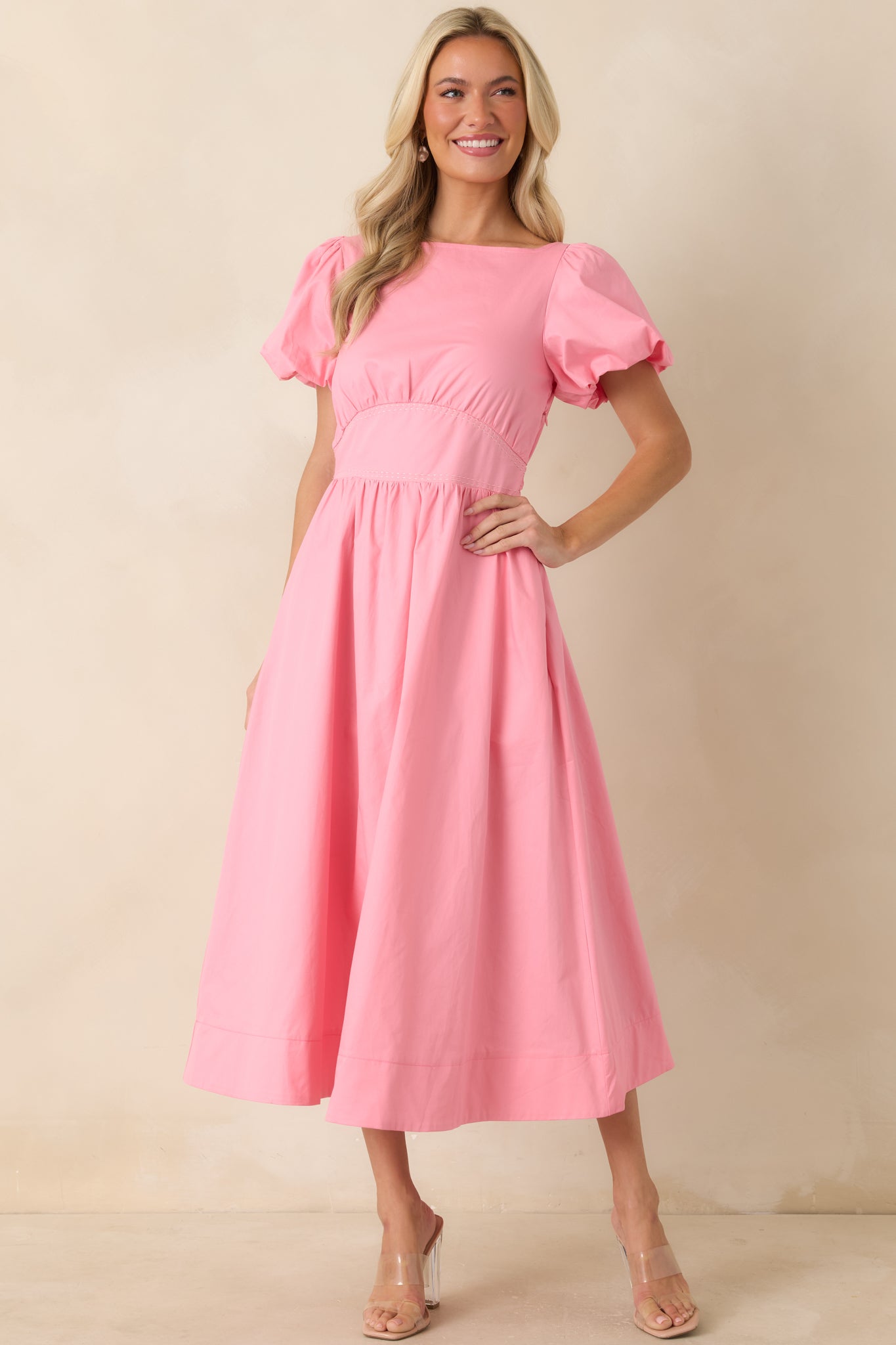Empire-waist pink dress with structured puff sleeves, side pockets, and a softly flared lined midi skirt.