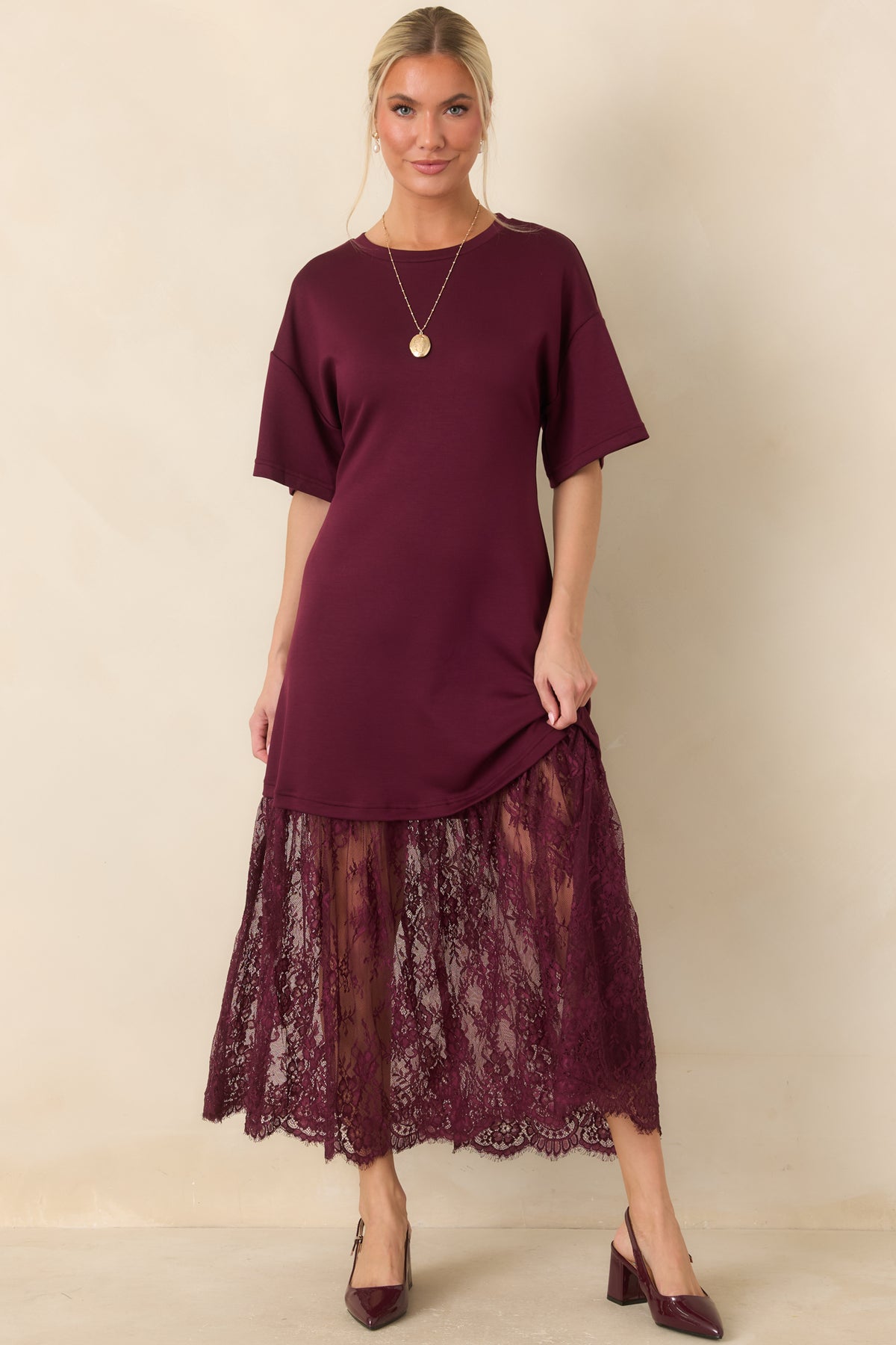 Short relaxed sleeves and a classic crew neckline give the plum dress a simple silhouette above its flared lace skirt.