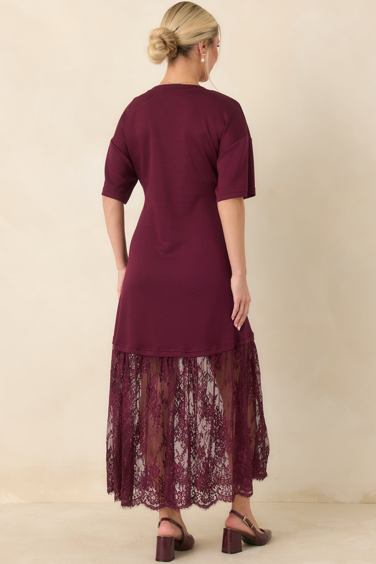 Rear view of the plum midi dress showing its crew neckline, relaxed short sleeves, and sheer floral lace skirt with a scalloped hem.