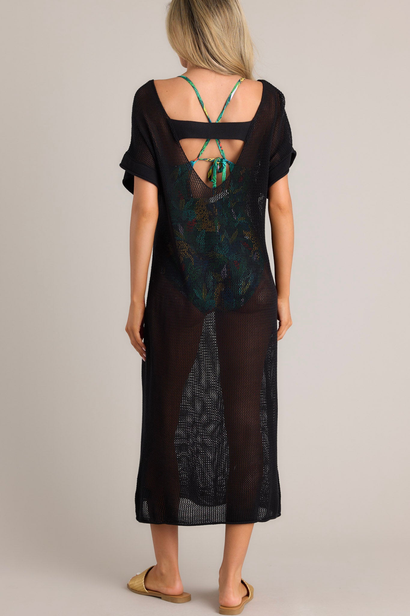 Back view of this black cover-up dress that features a wide rounded neckline, open back feature, an open-knit design, and cuffed short sleeves.