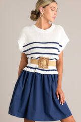 Angled front view of this navy dress that features a crew neckline, a ribbed knitted bodice, horizontal stripes, and a solid flowy skirt.