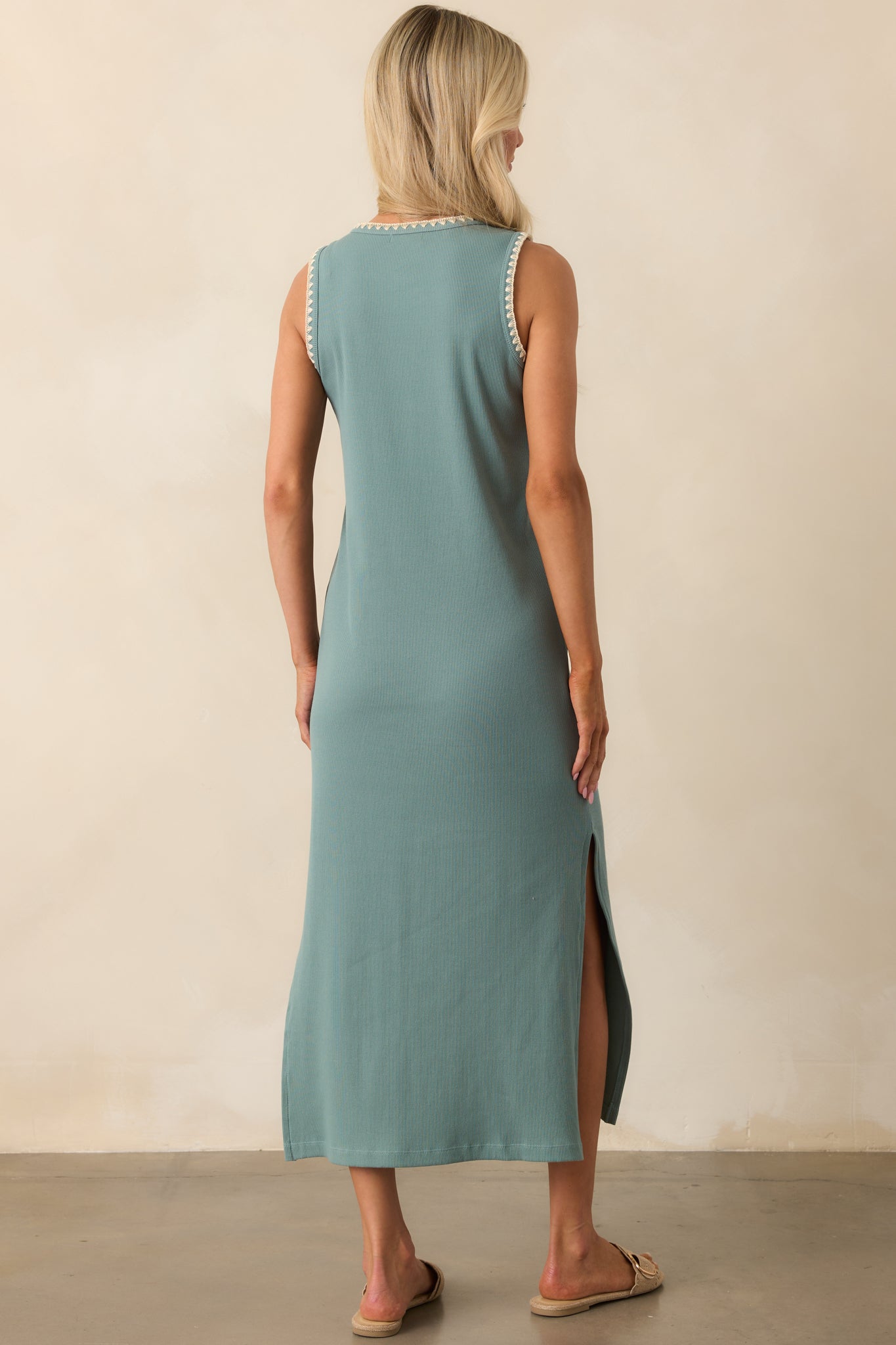 A view from behind displaying the ribbed texture, sleeveless design, and relaxed drape of the sage green midi dress.