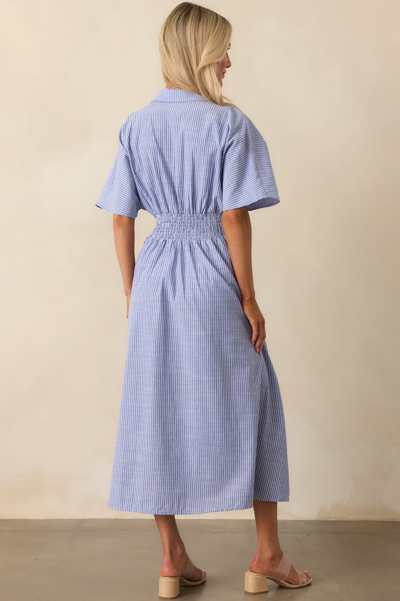 View from behind highlighting the smocked waist panel and continued stripe pattern of the blue midi dress.