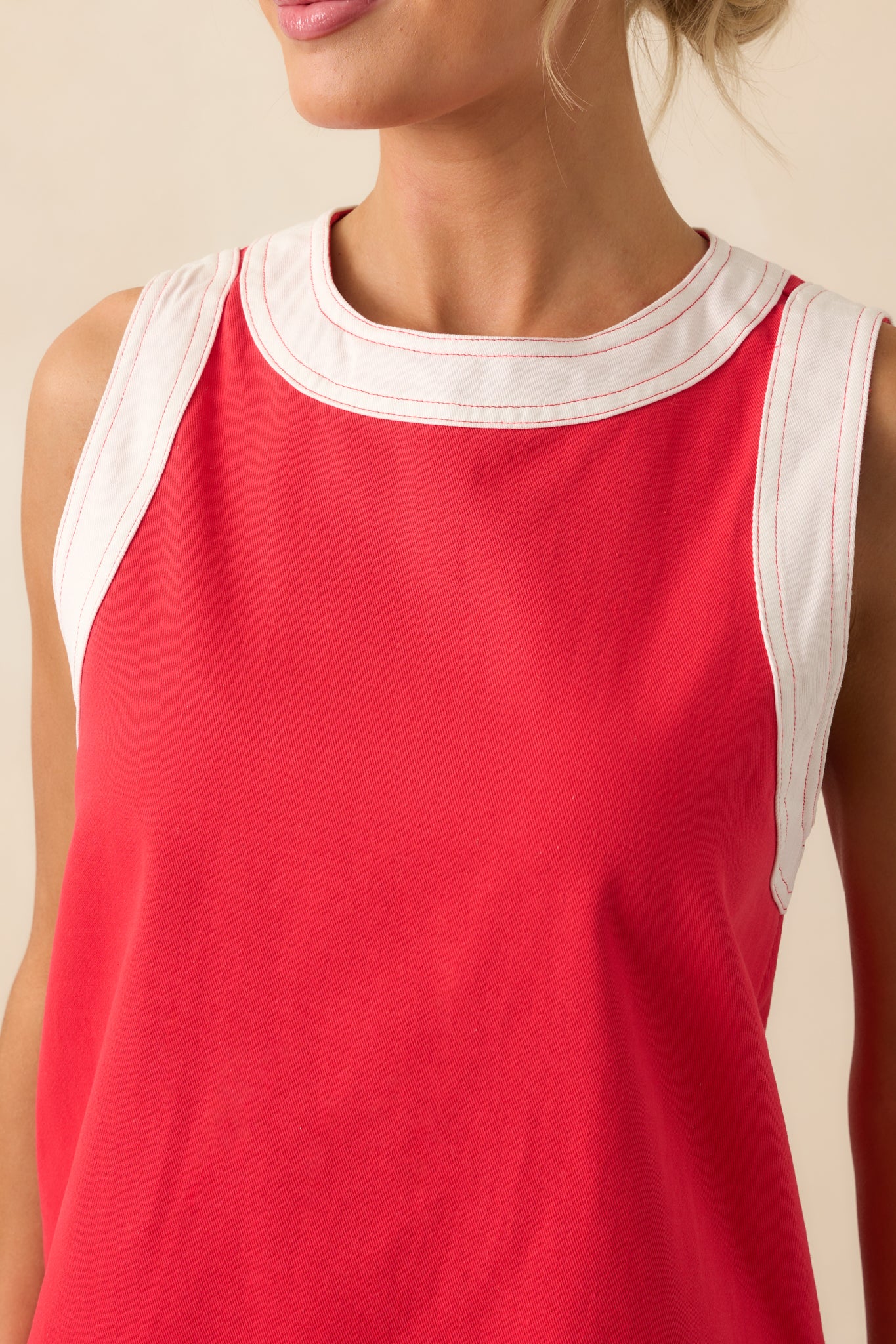 Close-up detail of the red mini dress fabric and contrast white trim along the neckline.