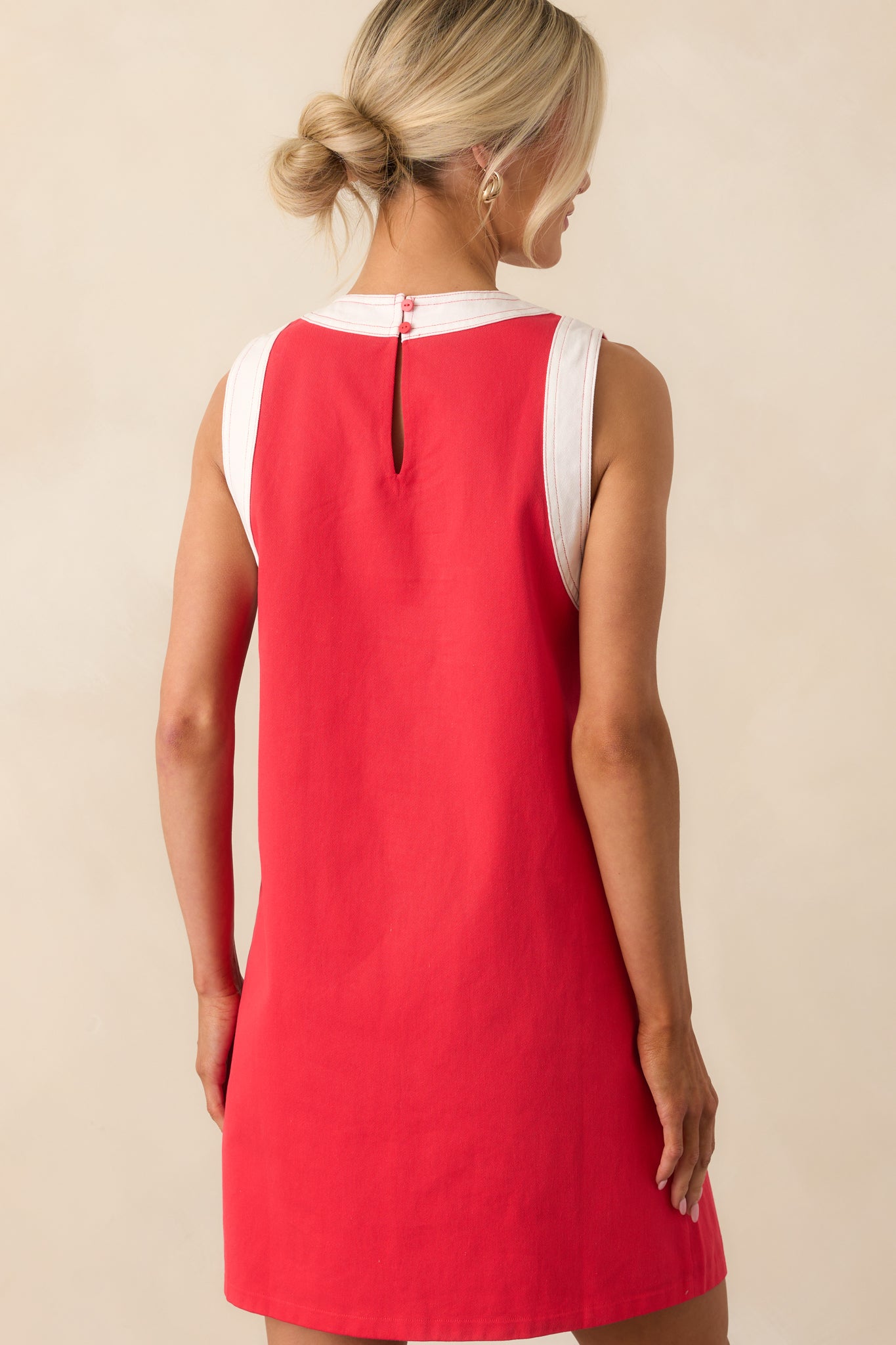 A view from behind showing the keyhole button closure and white trim along the neckline of the red mini dress.