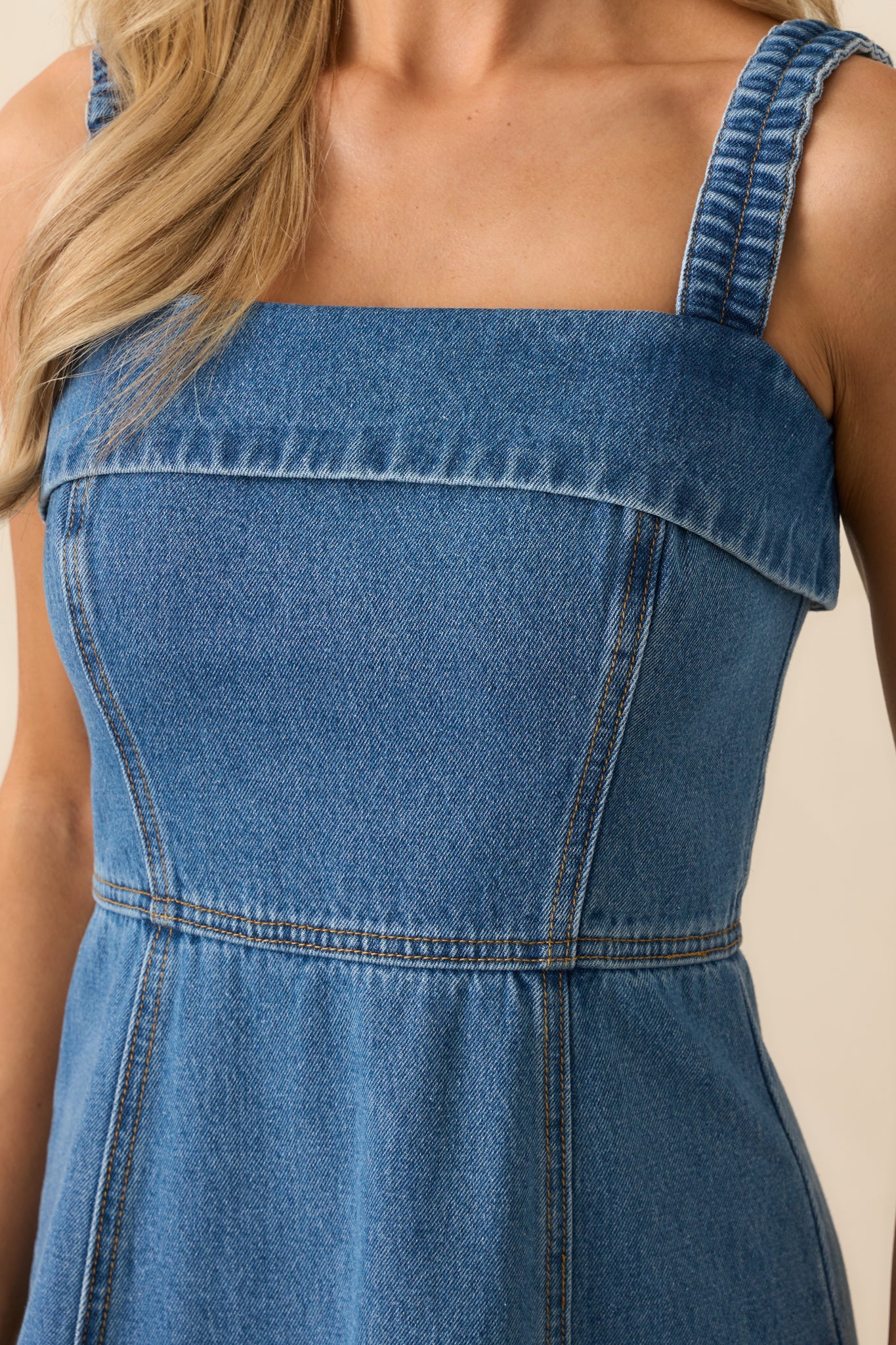 Zoomed-in view of the bodice area, showing the square neckline, tan topstitching, and texture of the medium wash fabric.