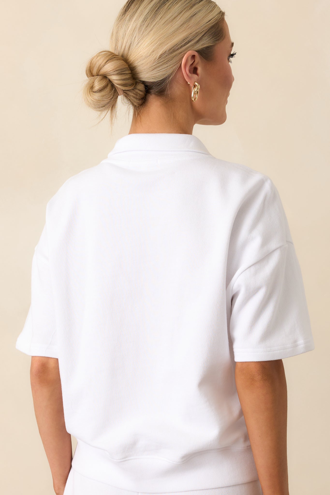 A view from behind showing the collar, short sleeves, and oversized shape of the white sweatshirt.