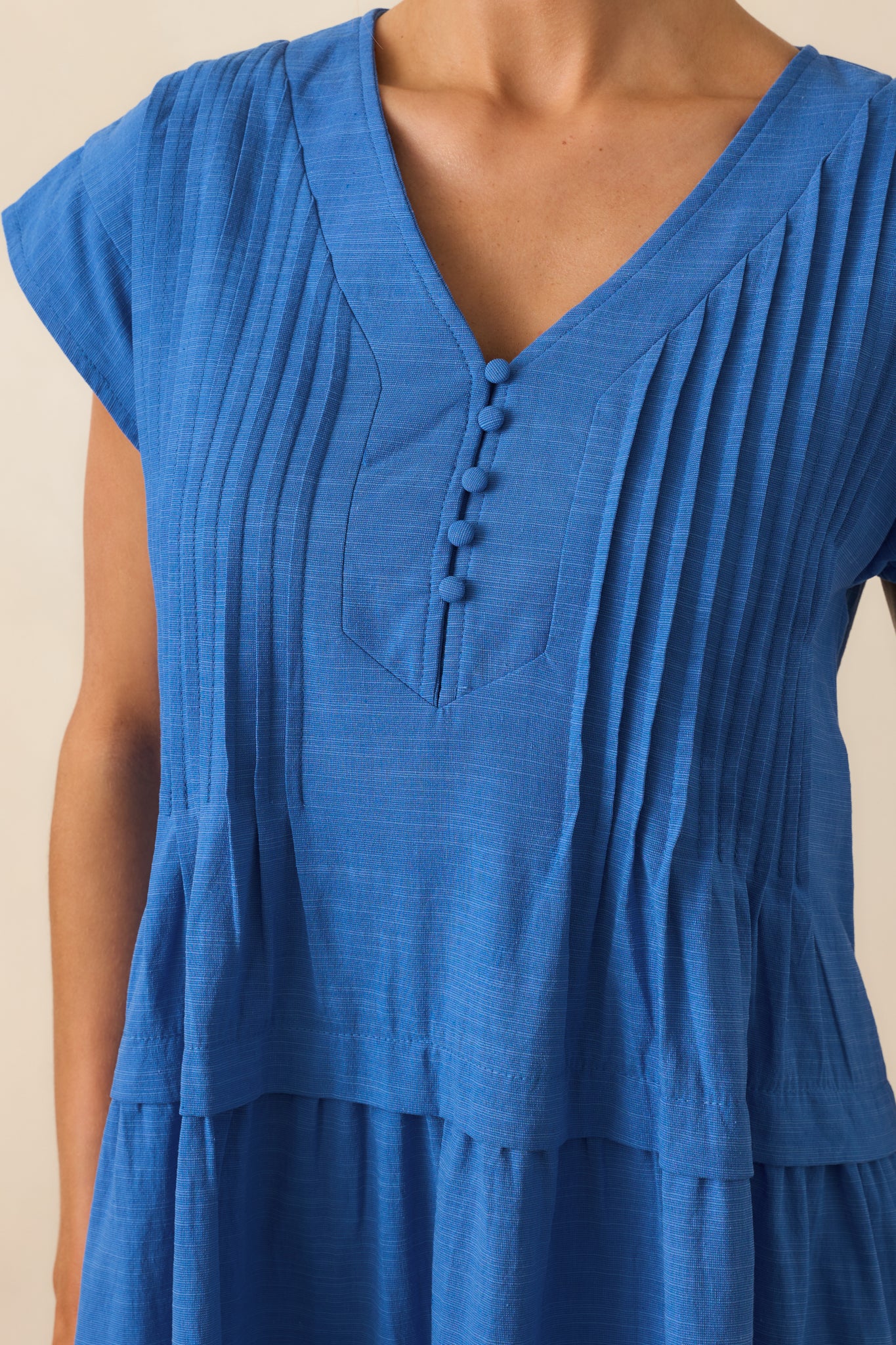 Tight detail shot showing the fine pintuck stitching and fabric texture on the cobalt blue dress.