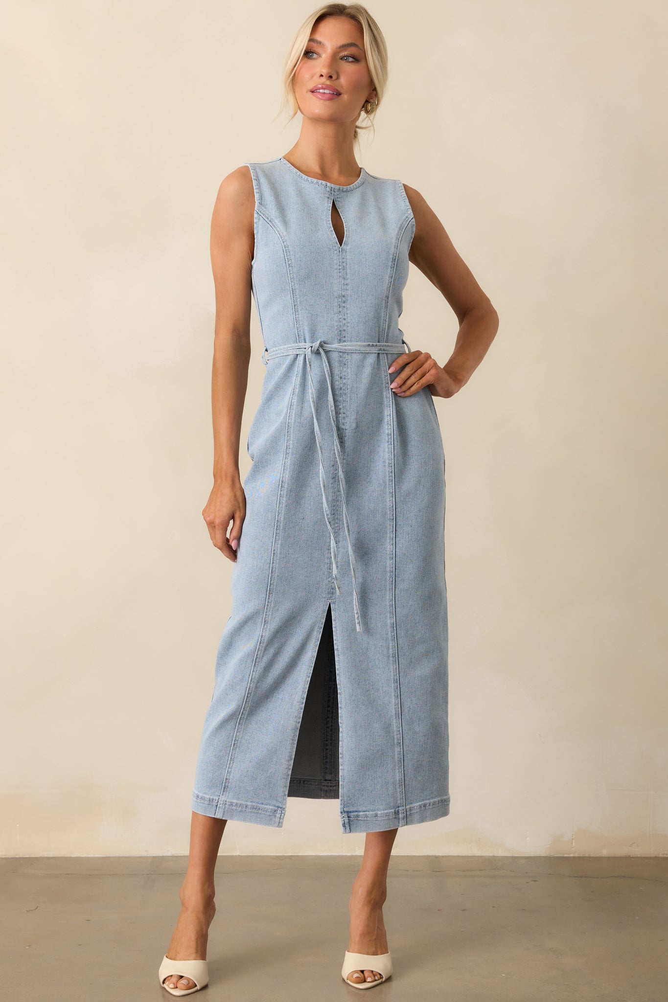 Full body image of a sleeveless midi dress with a belted waist and soft light denim tone.