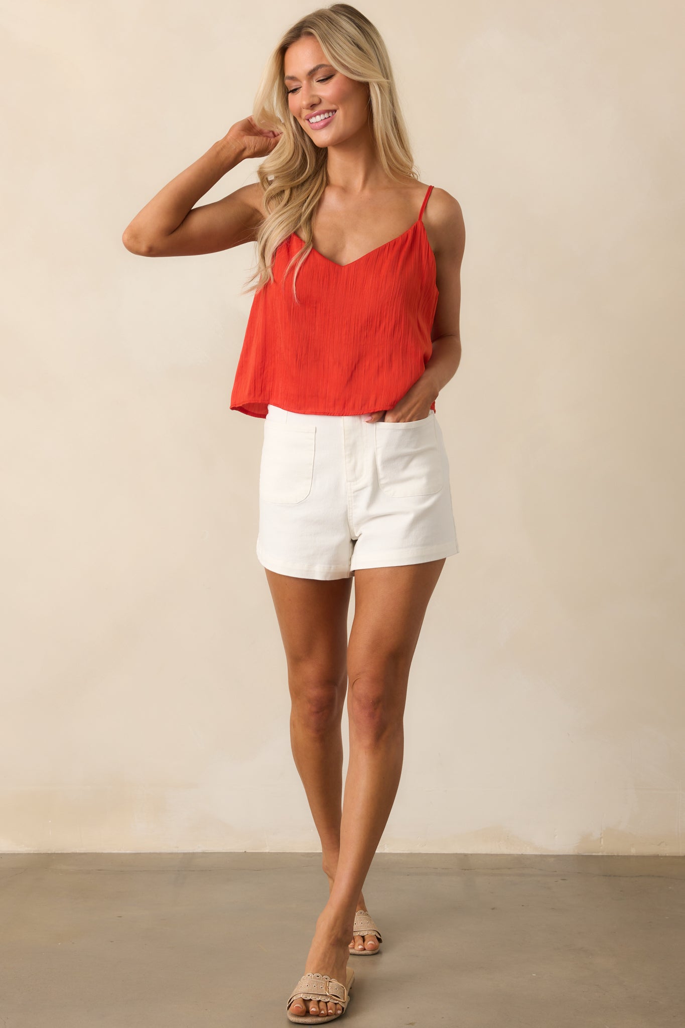 Full-length image of the red top, emphasizing its flowy silhouette and contrast sage green lining at the hem.