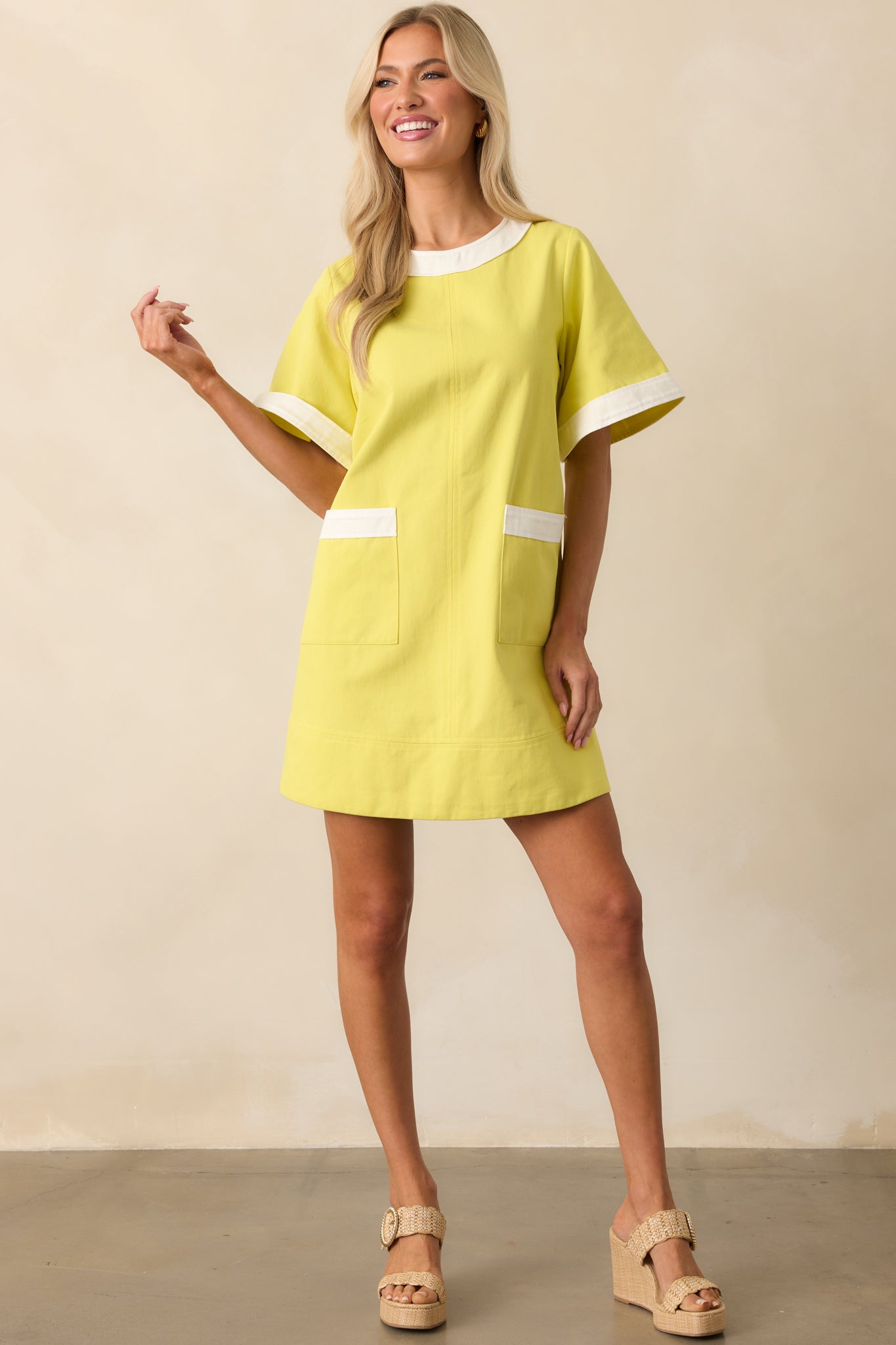 Full body view of the yellow mini dress showing the round neckline, short sleeves, and white contrast trim.