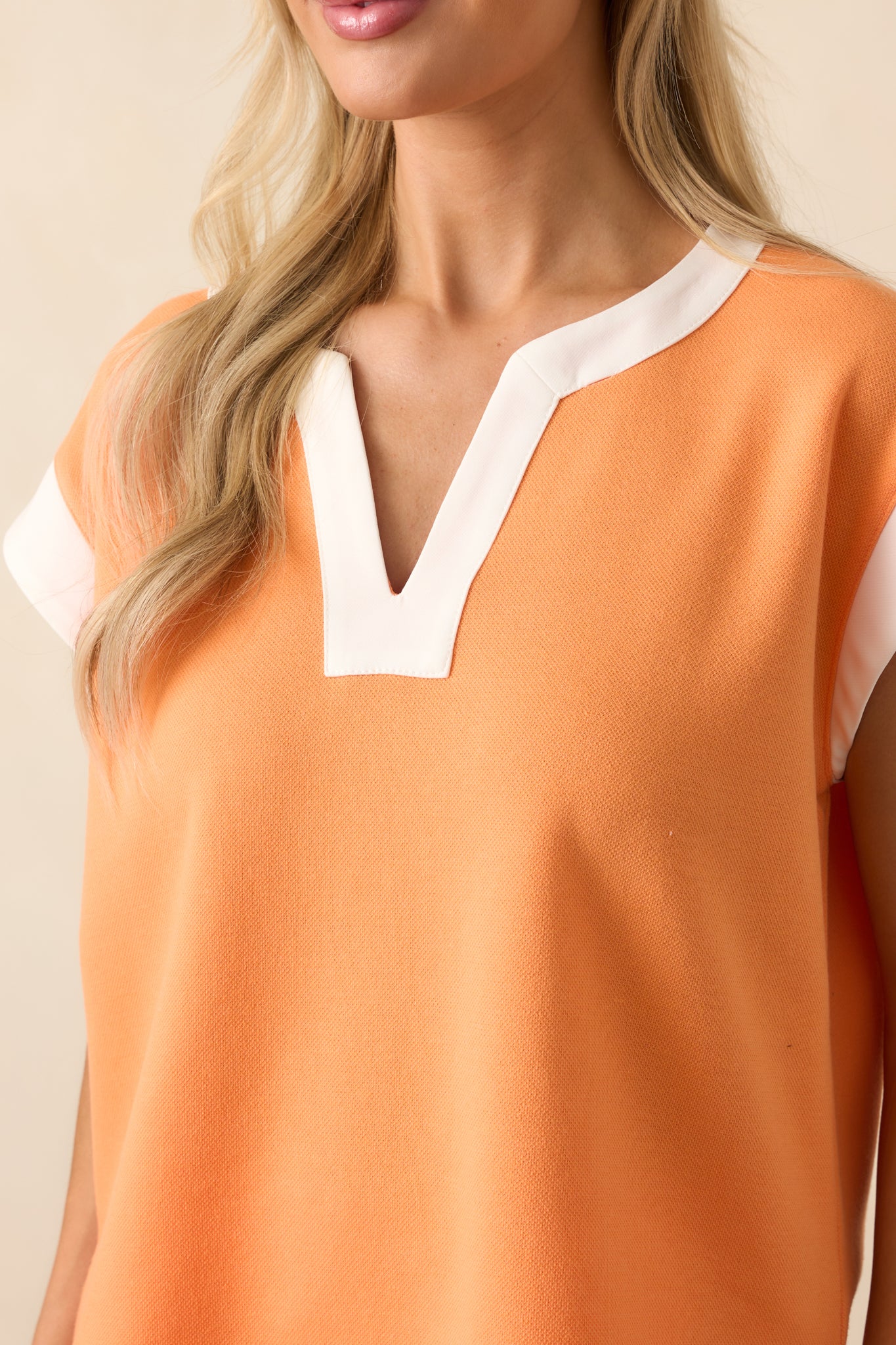Close-up of the notch v-neckline and white contrast trim, showing stitching and fabric detail.