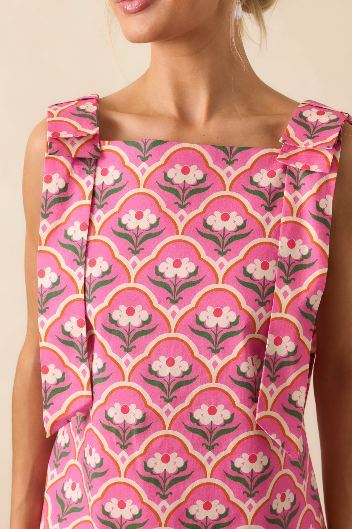 Close-up of the square neckline and bow shoulder detail, with visible stitching and print accents.