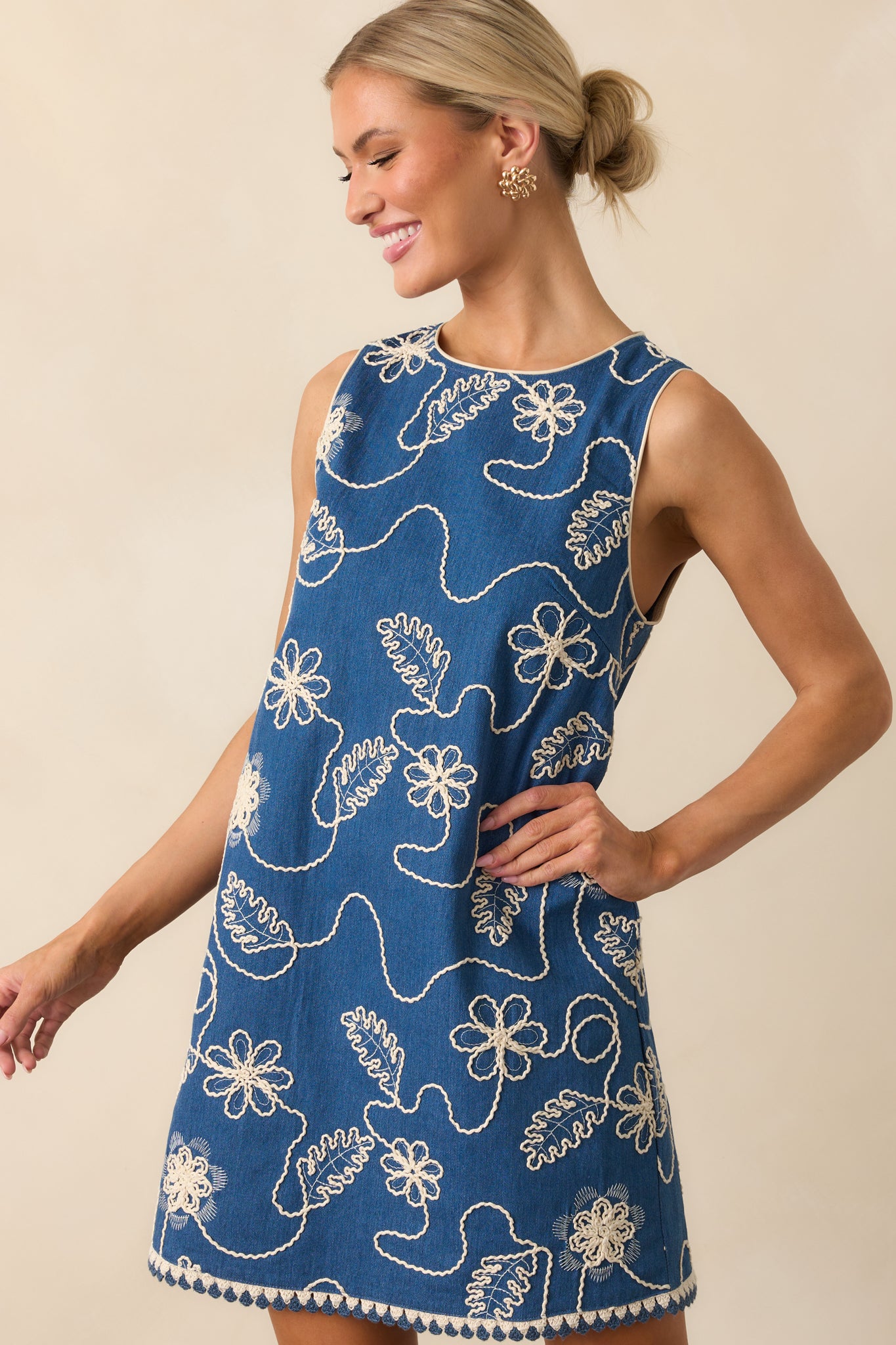 Side angle crop capturing the sleeveless armhole, contrast piping along the seam, and the textured floral stitching.