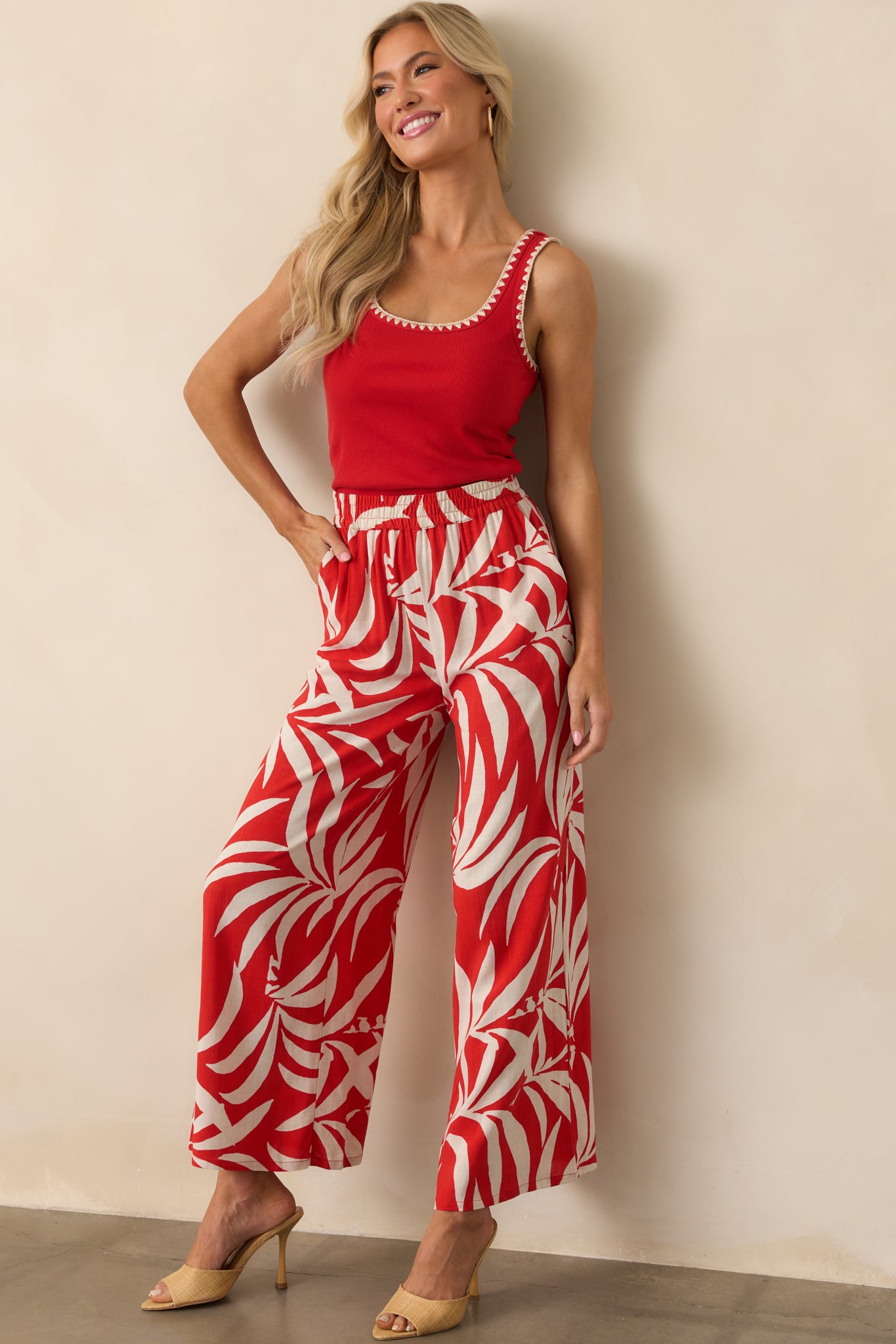 Red high-rise pants with an ivory tropical print and wide-leg silhouette, styled to show their flowy, relaxed shape.